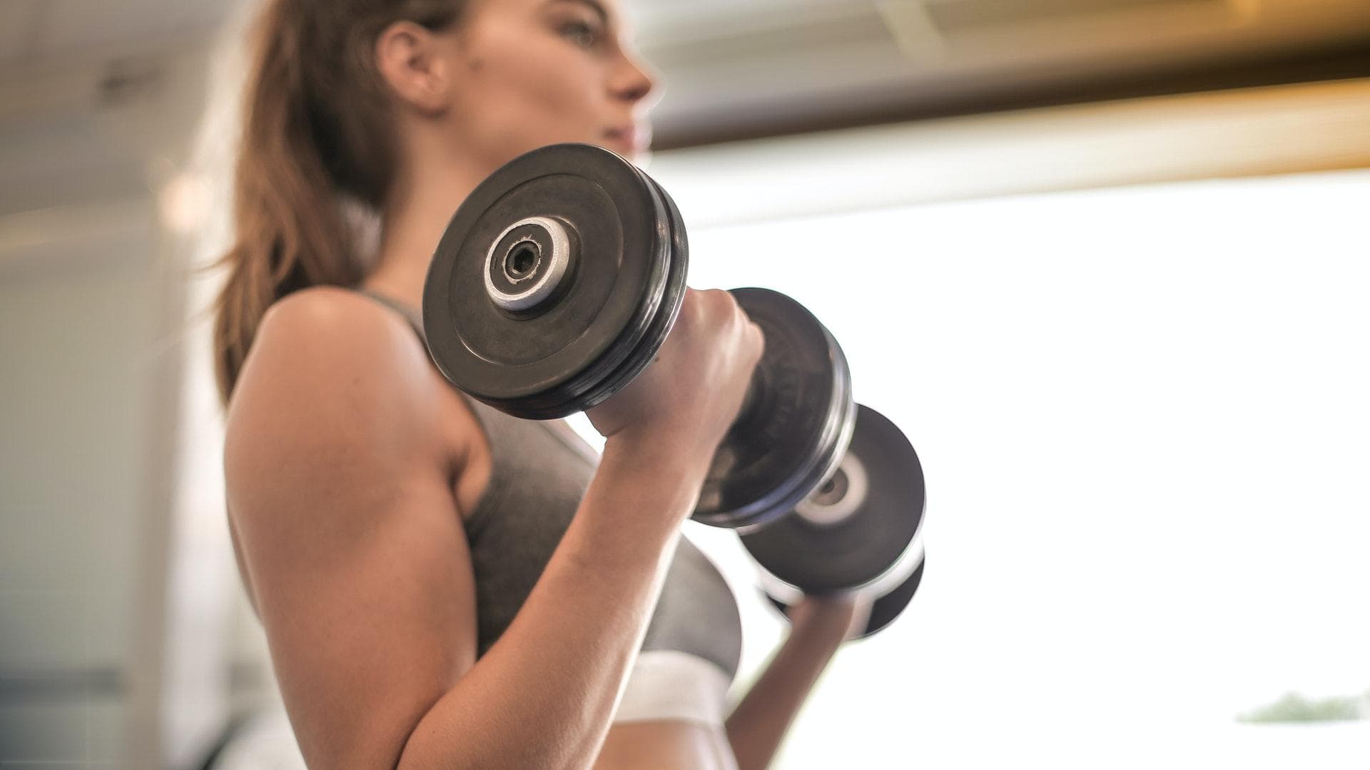 Frau macht Bizeps-Curls mit Hanteln
