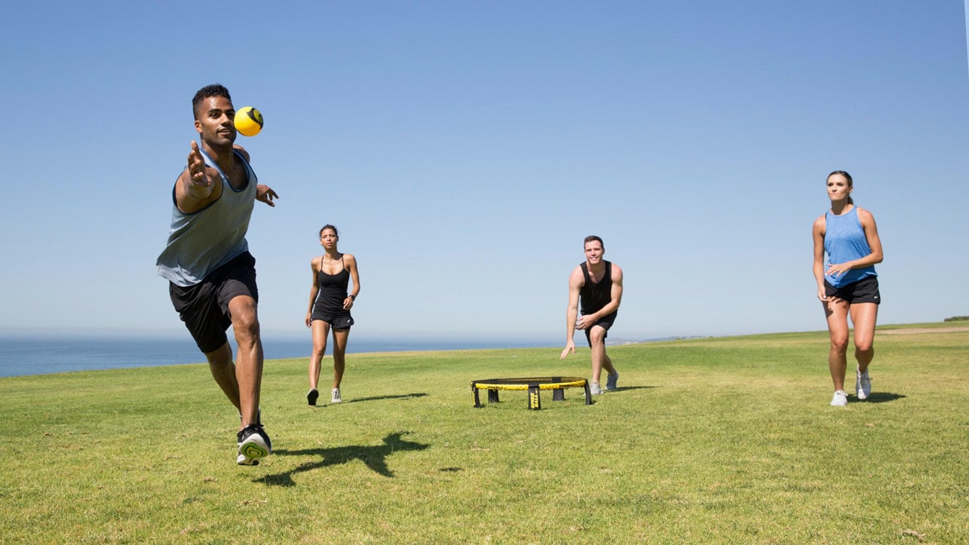 Menschen spielen auf einer Wiese Spikeball