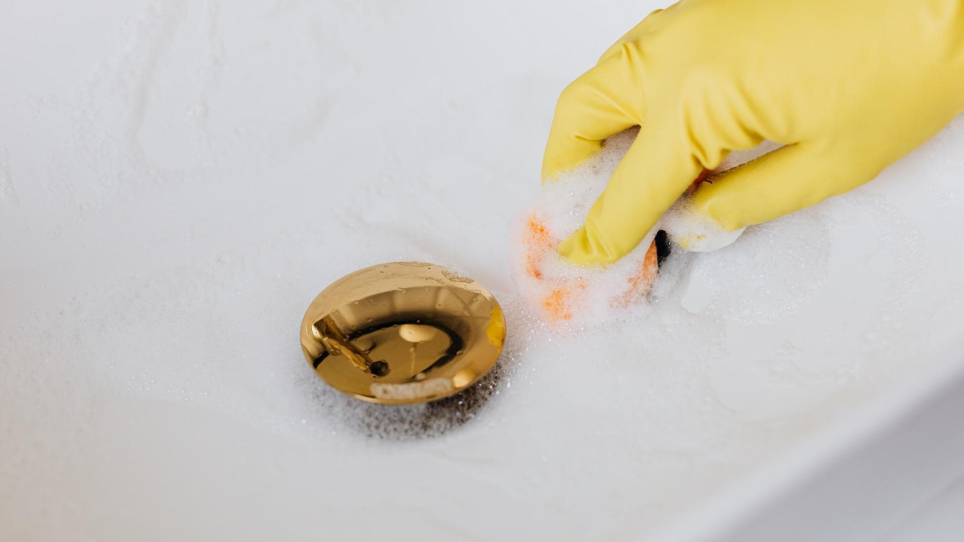 Mit Handschuhen das Waschbecken putzen