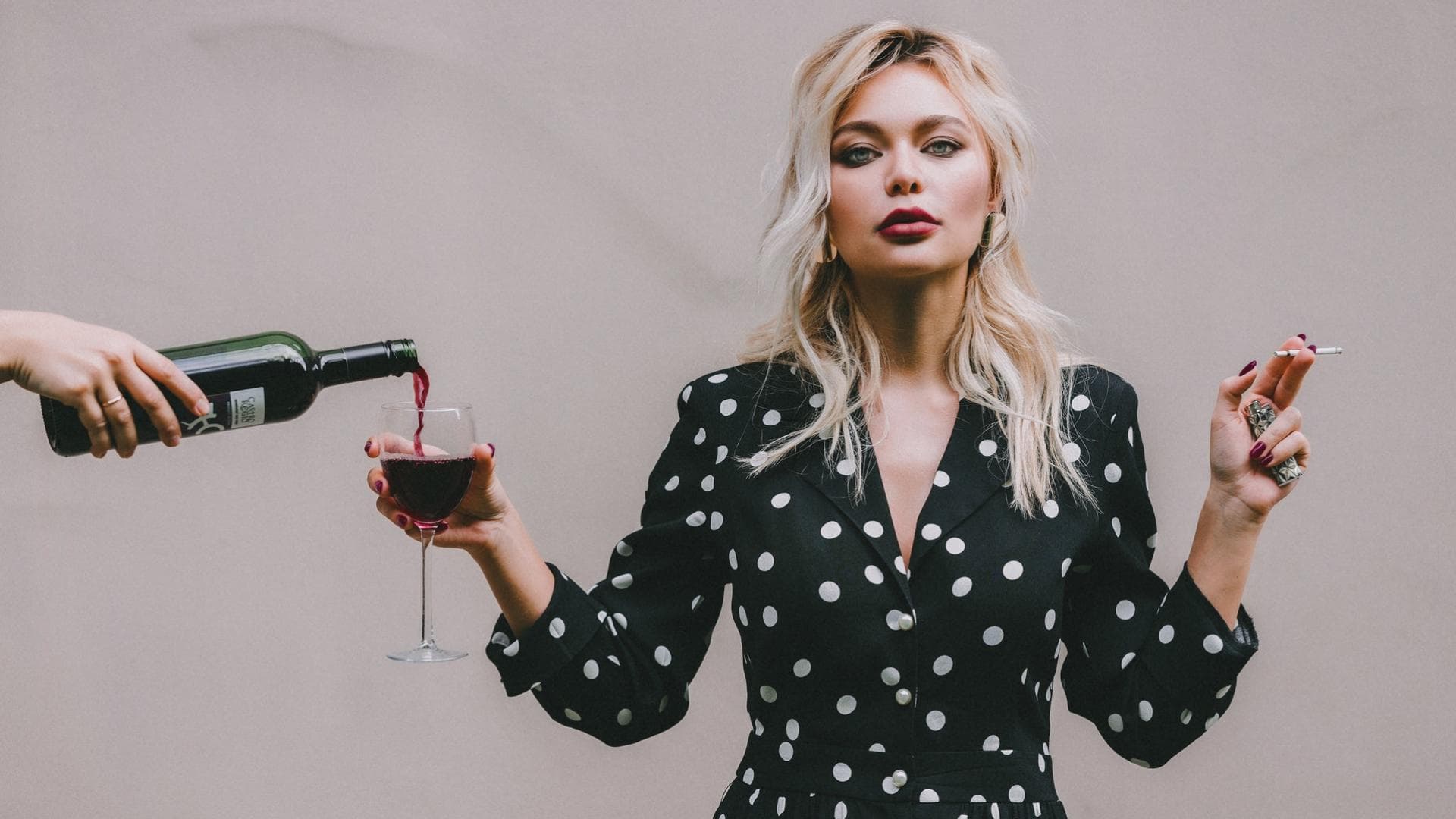 Frau mit Glas Rotwein und Zigarette in der Hand