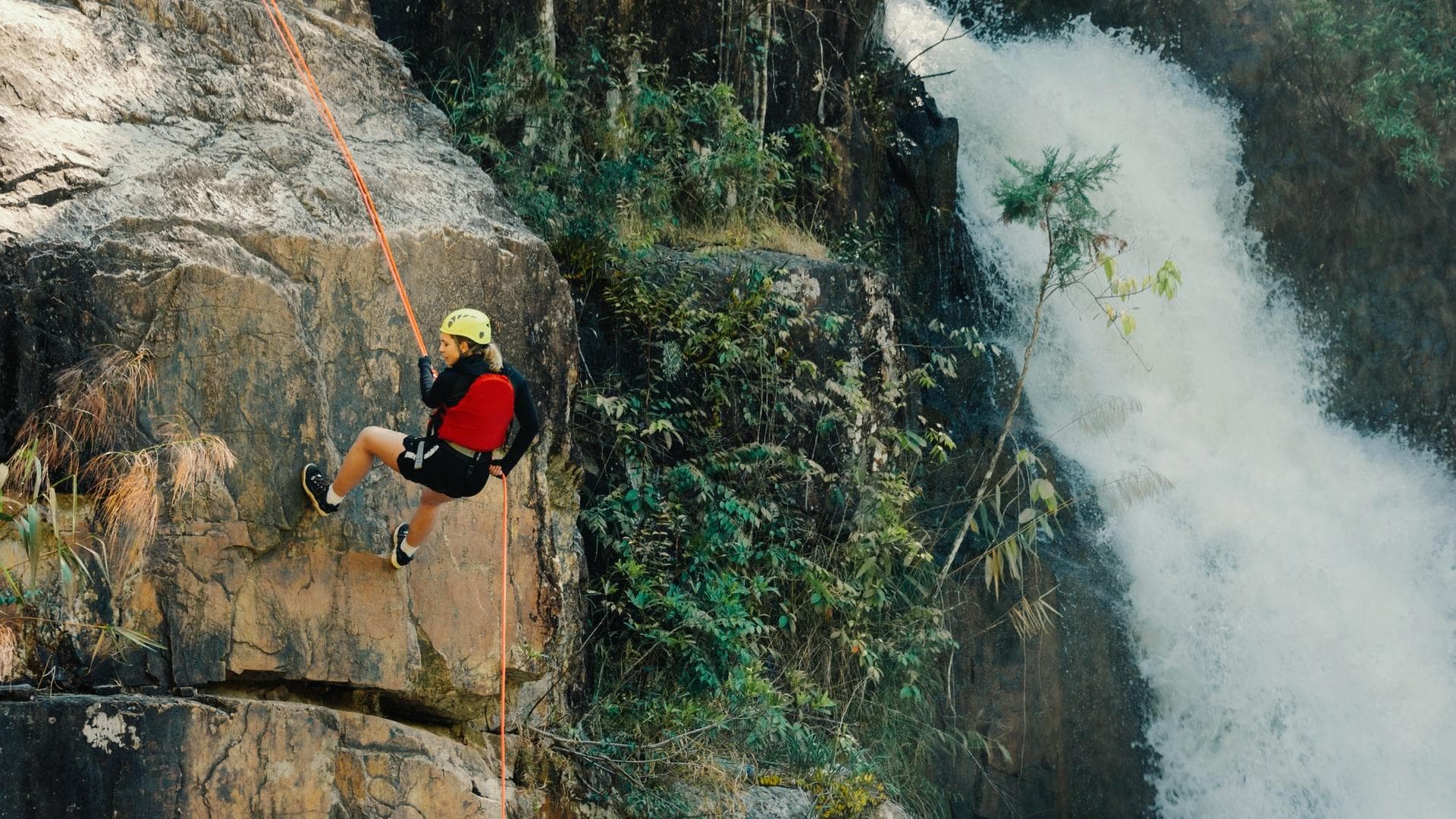 Kletterin seilt sich am Fels ab Kletterin seilt sich am Fels ab