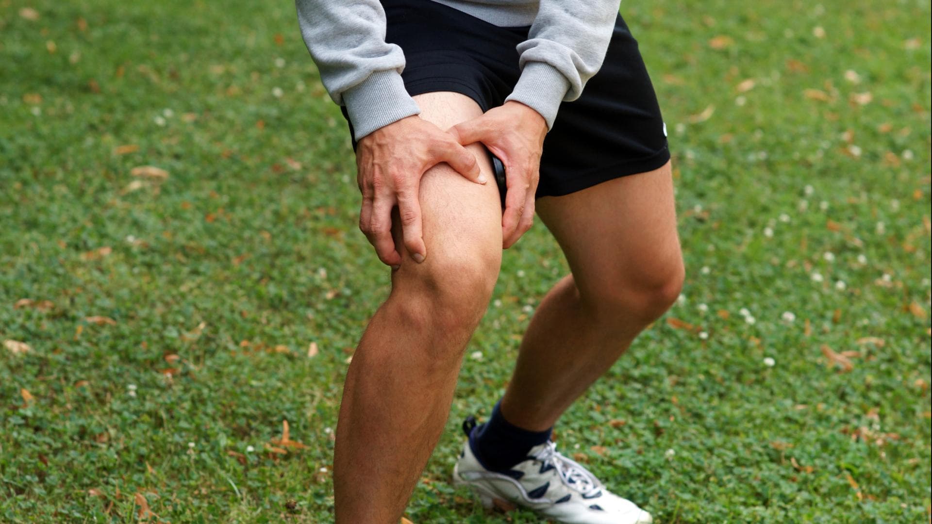 Mann greift sich vor Schmerzen ans Knie