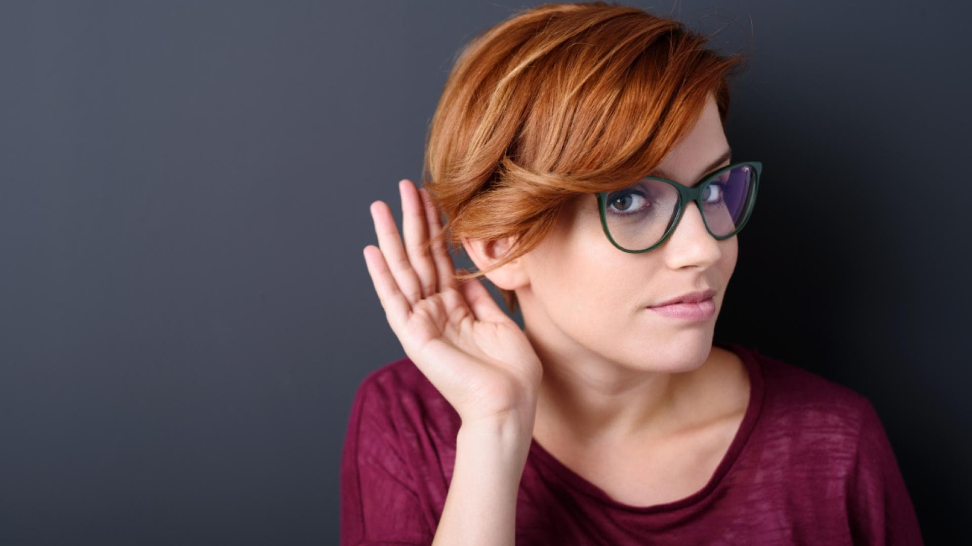 Frau hält sich eine Hand ans Ohr
