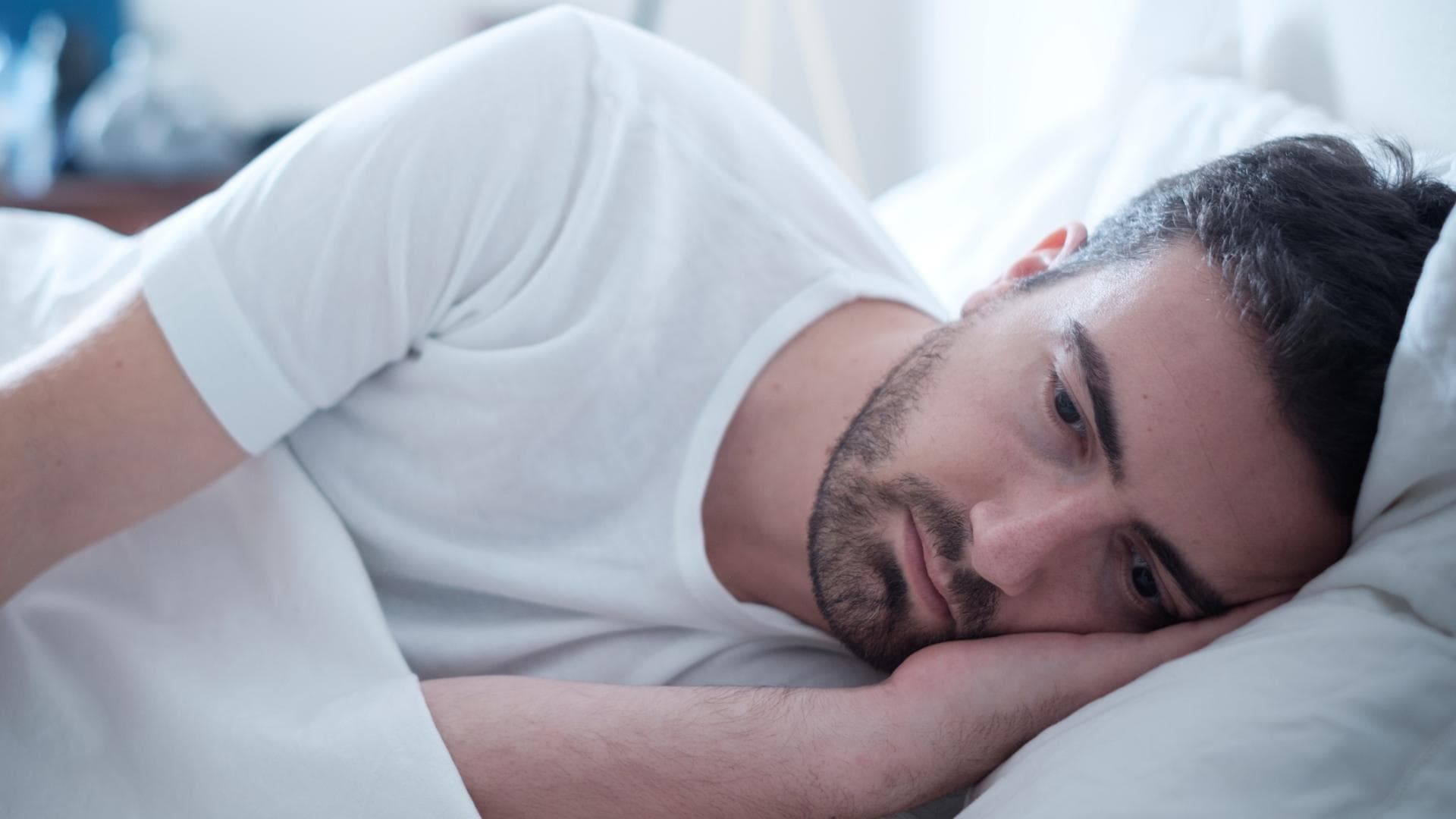 Mann liegt traurig im Bett Mann liegt traurig im Bett