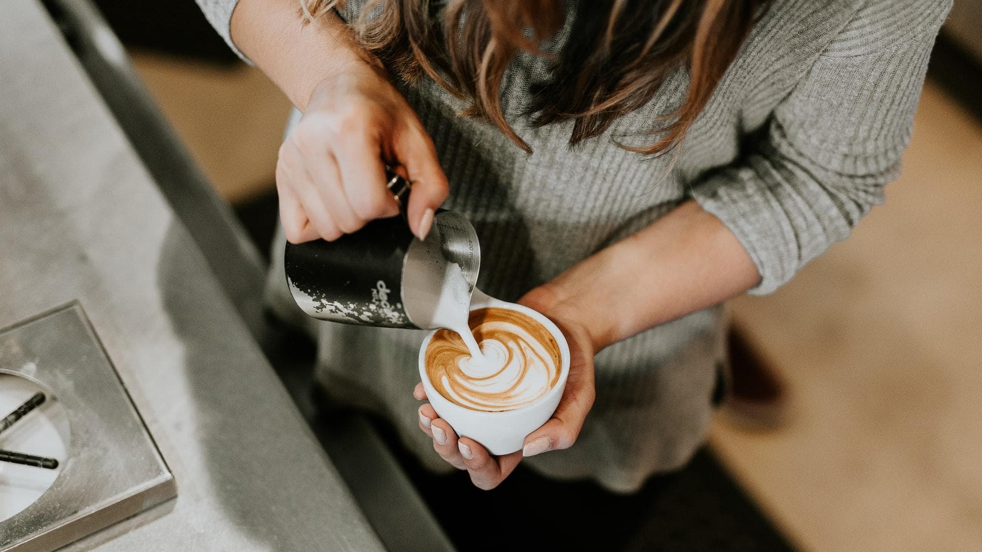 Frau bereitet Milchkaffee zu Frau bereitet Milchkaffee zu