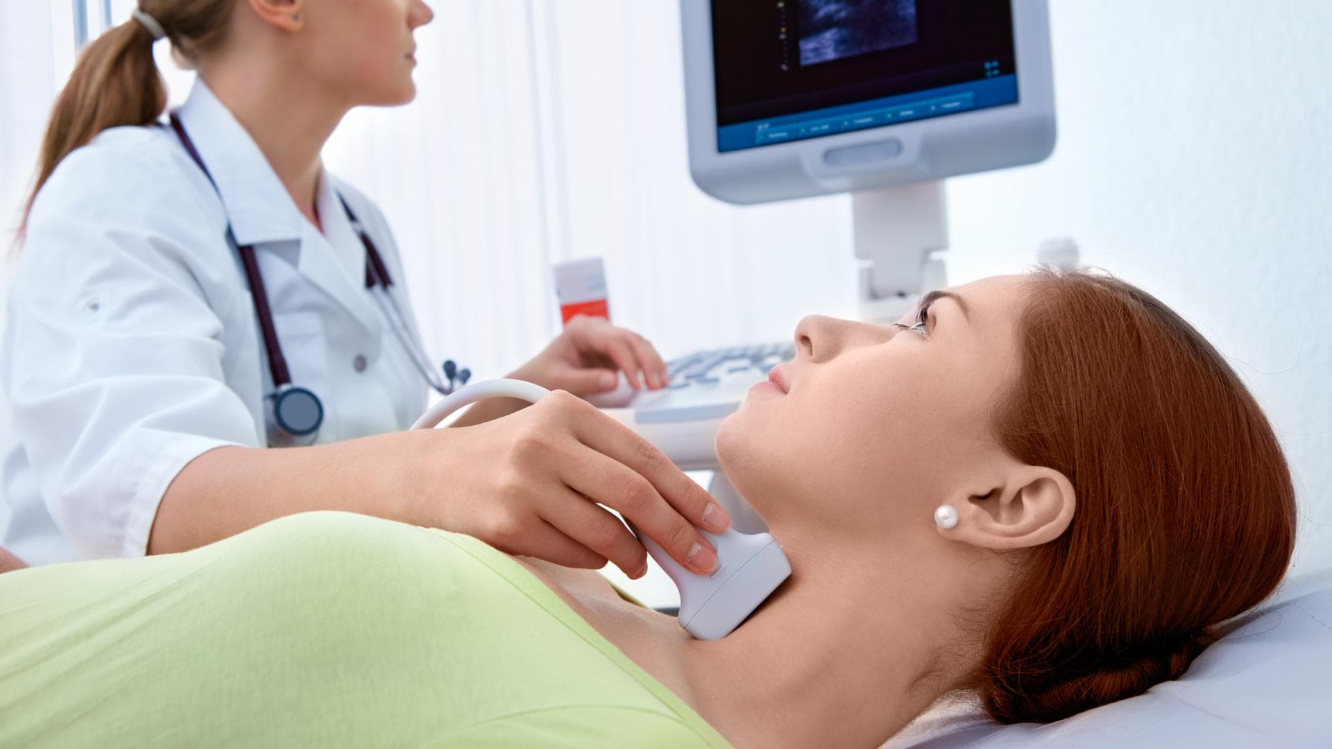 Ärztin untersucht die Schilddrüse einer Frau mittels Ultraschall