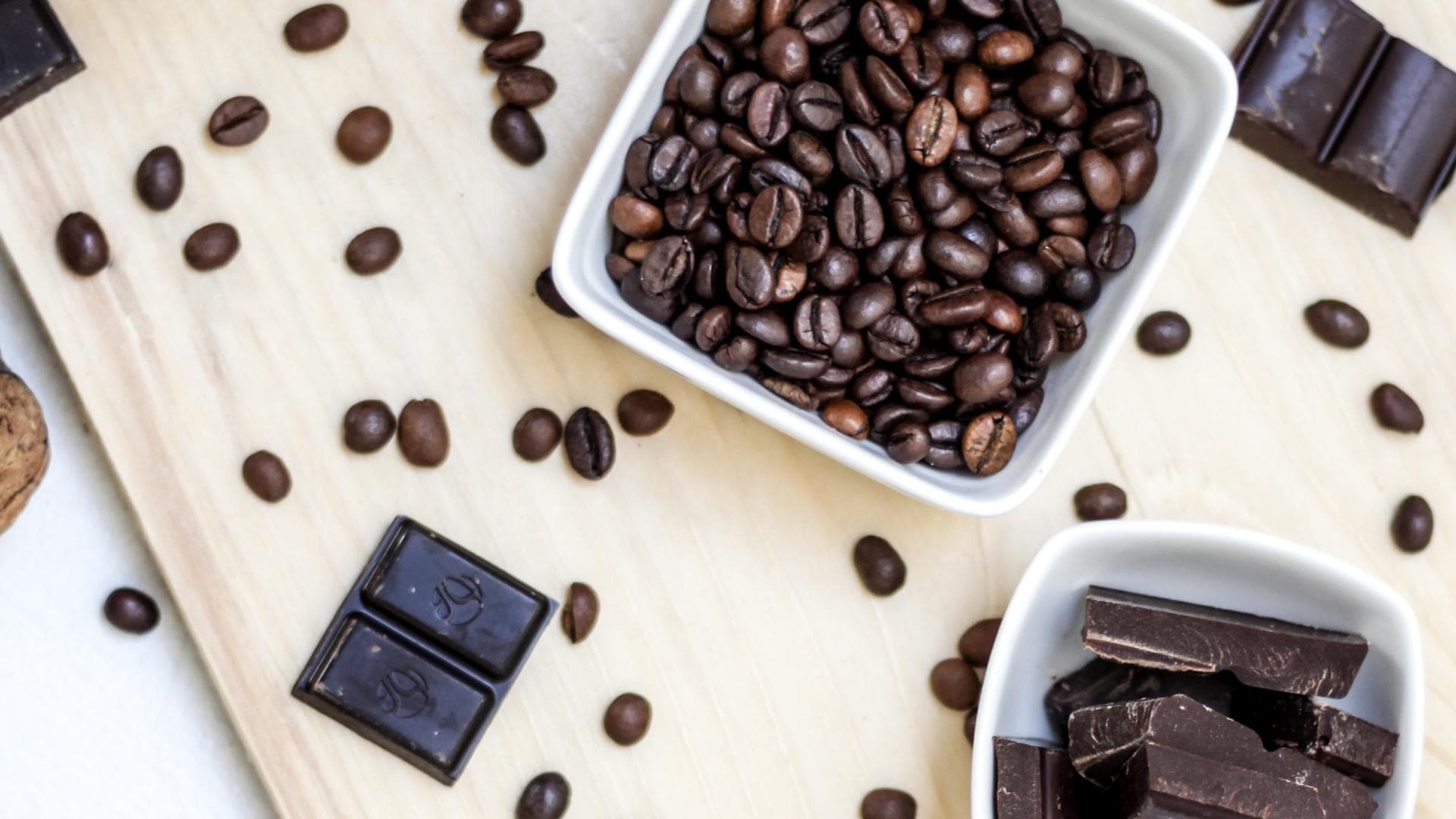 Zartbitterschokolade und Kaffee liefern gesunde Bitterstoffe Küchentischdisplay mit Zartbitterschokolade, Kaffeebohnen, Nüssen und Kakaopulver