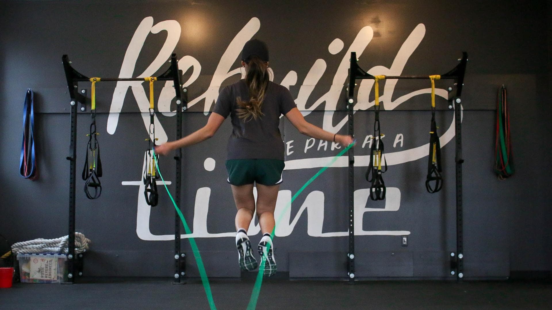 Frau beim Springseilspringen mit grünem Seil im Gym