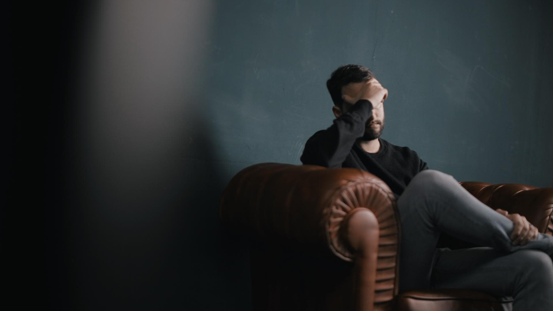 Mann mit Depressionen sitzt betrübt in Sessel
