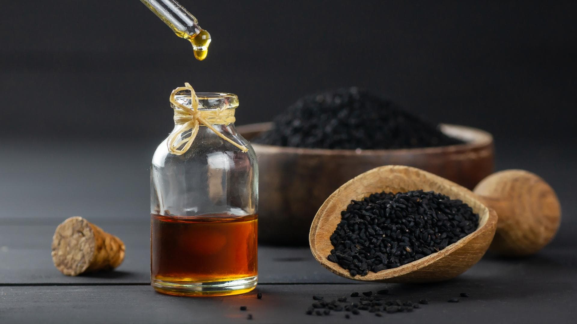 Schwarzkümmelöl und Schwarzkümmelsamen auf schwarzem Tisch
