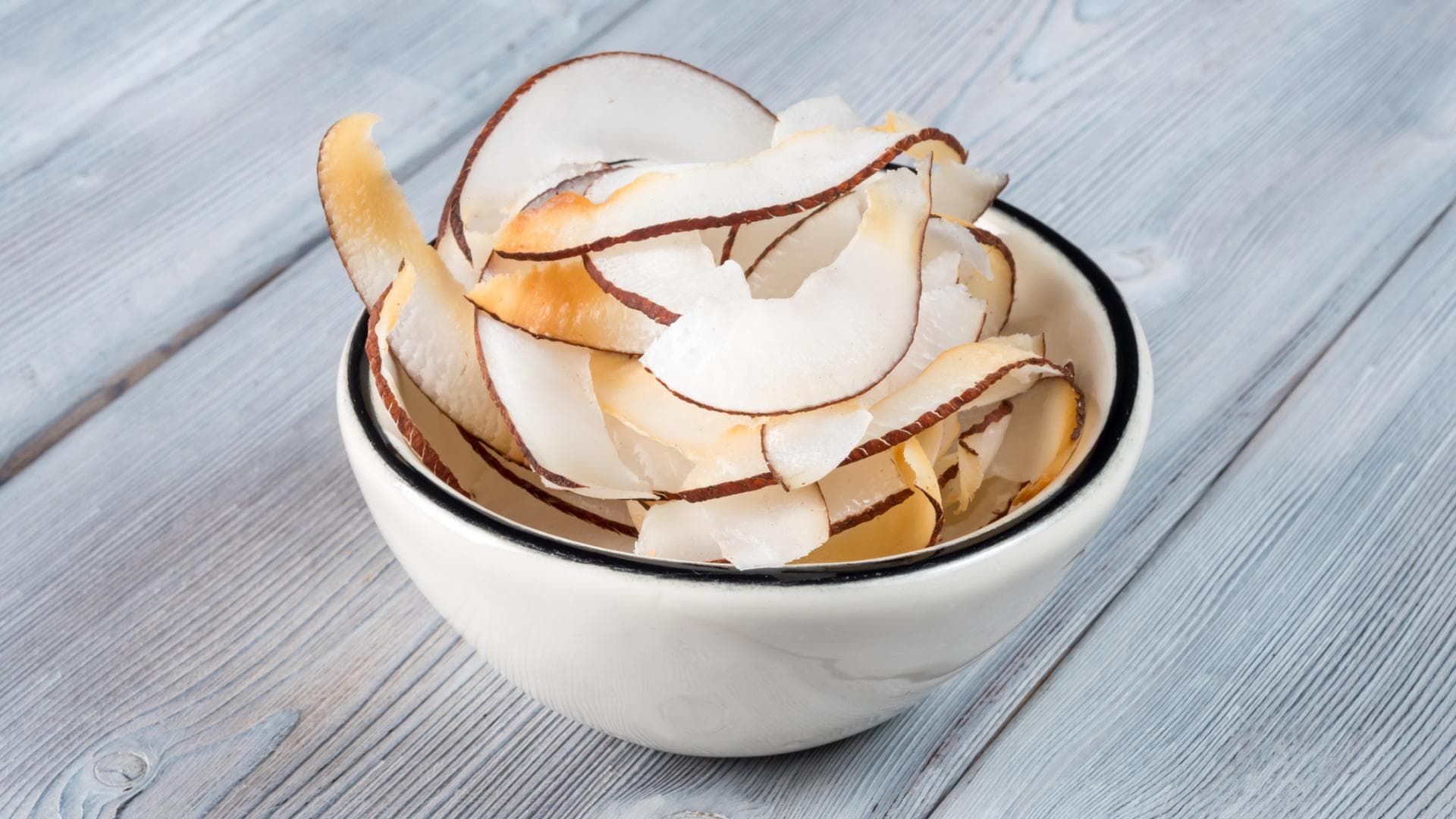 Kokoschips in weißer Schale auf Holzuntergrund