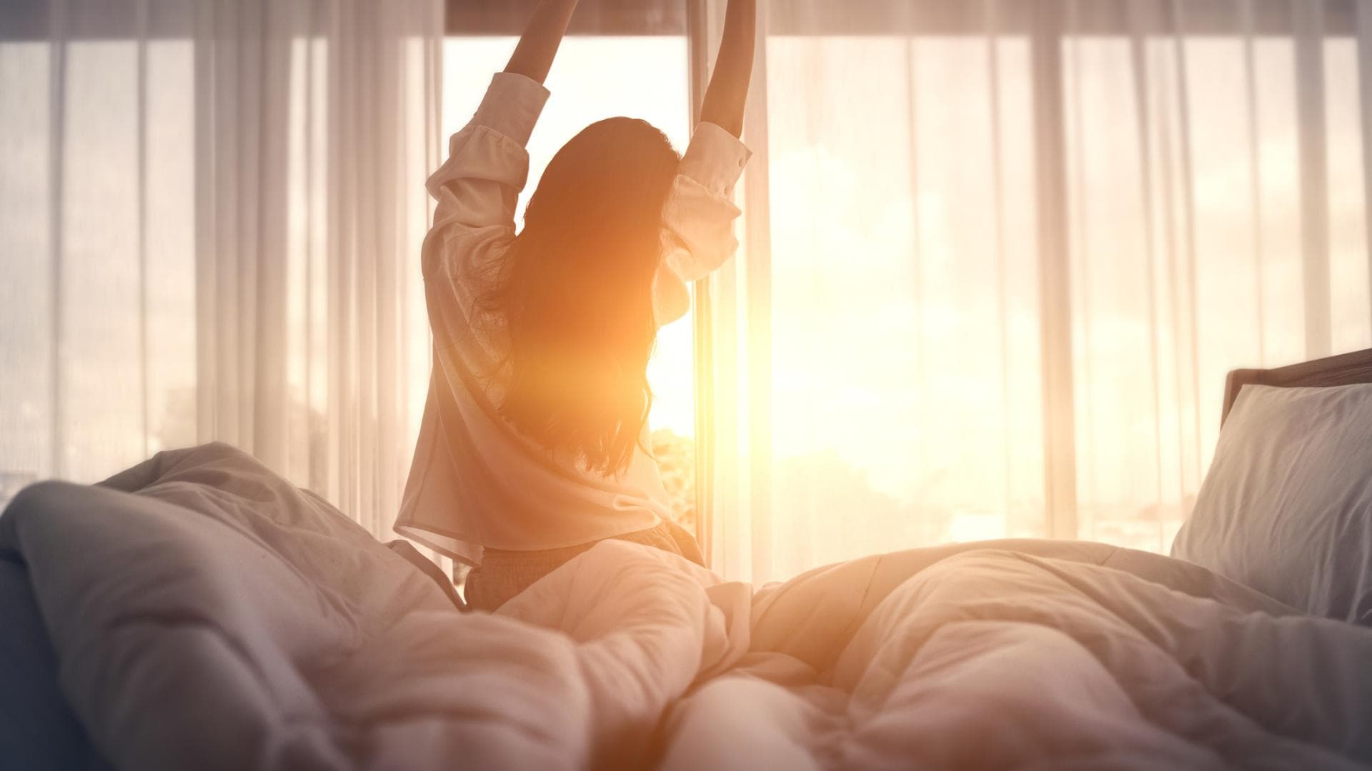 früh aufstehen macht schlank Frau steht erholt und putzmunter früh am Morgen auf