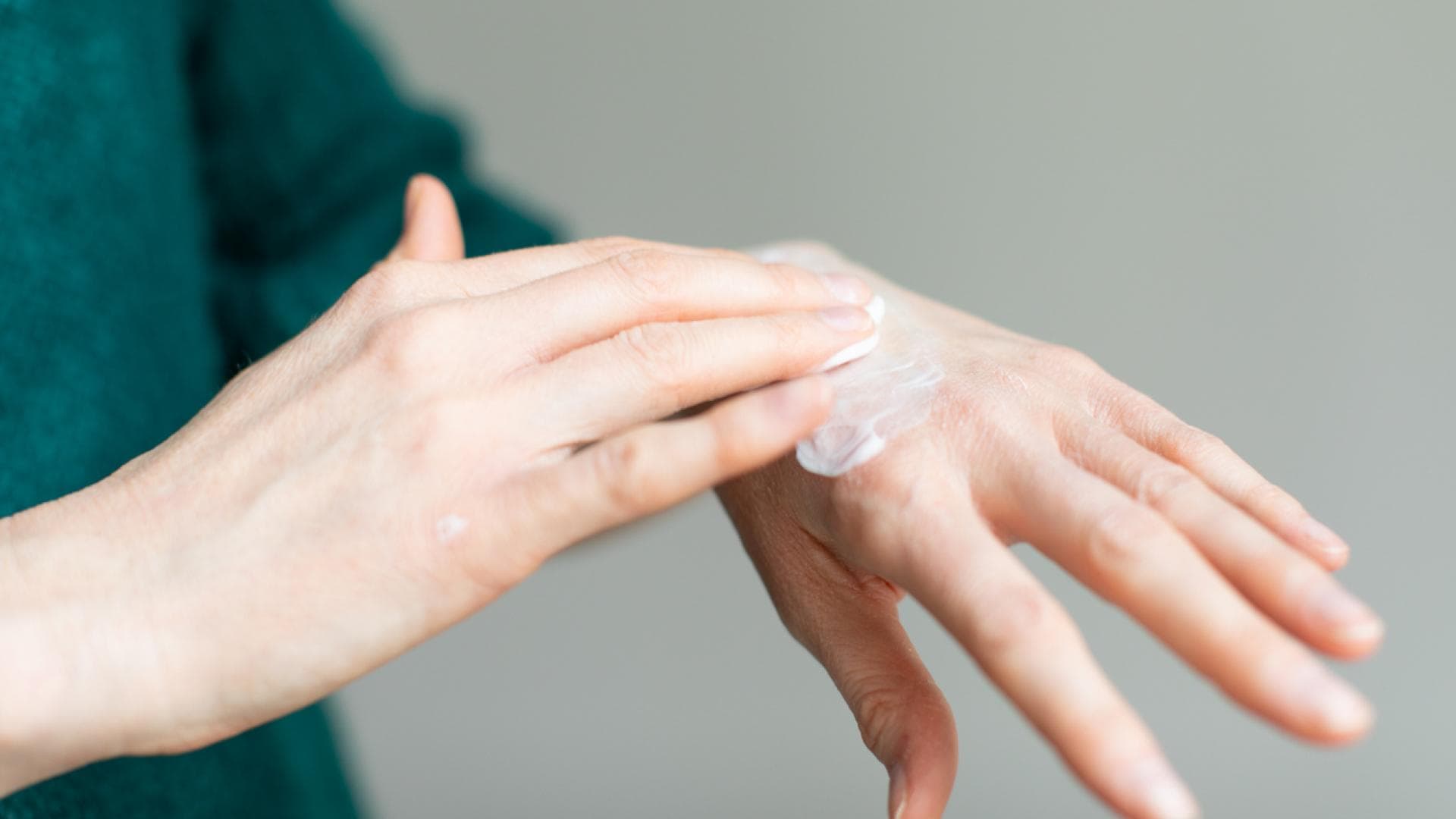 Frau trägt Creme auf Handrücken auf