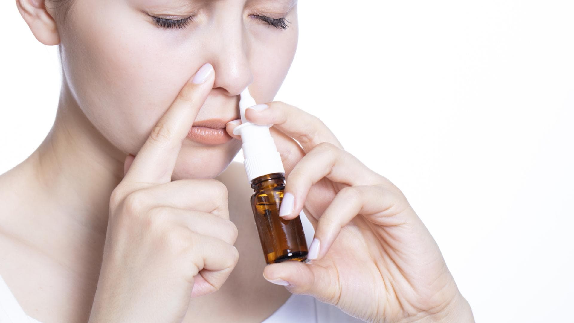 Frau sprüht Nasenspray in ihr linkes Nasenloch