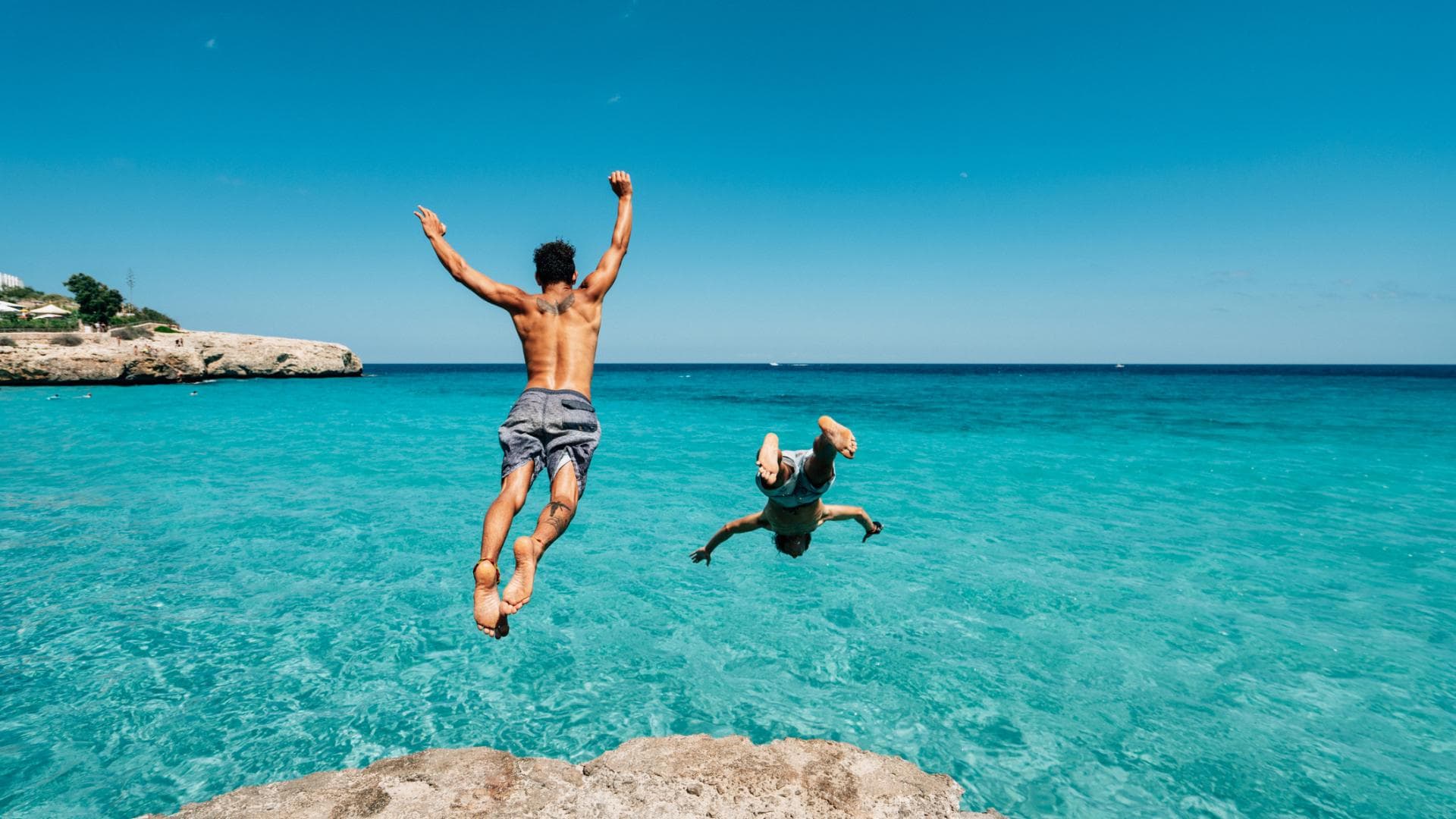 zwei junge Männer springen ins Meer