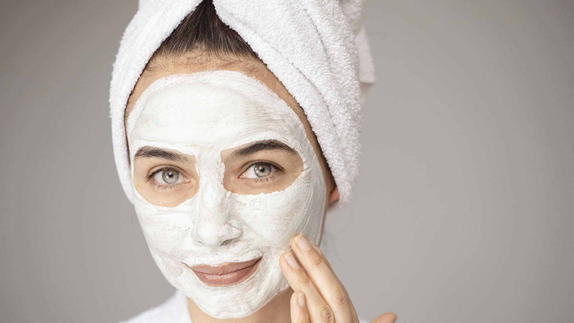 junge Frau trägt Creme-Maske auf Gesicht auf