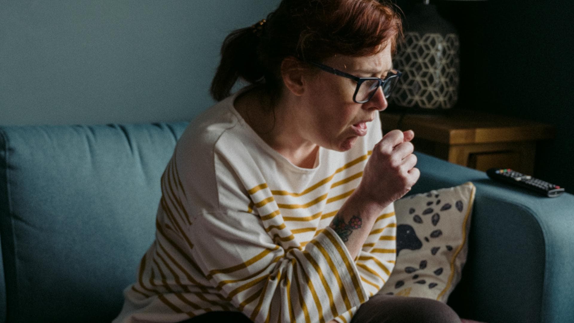 Frau hustet auf Couch