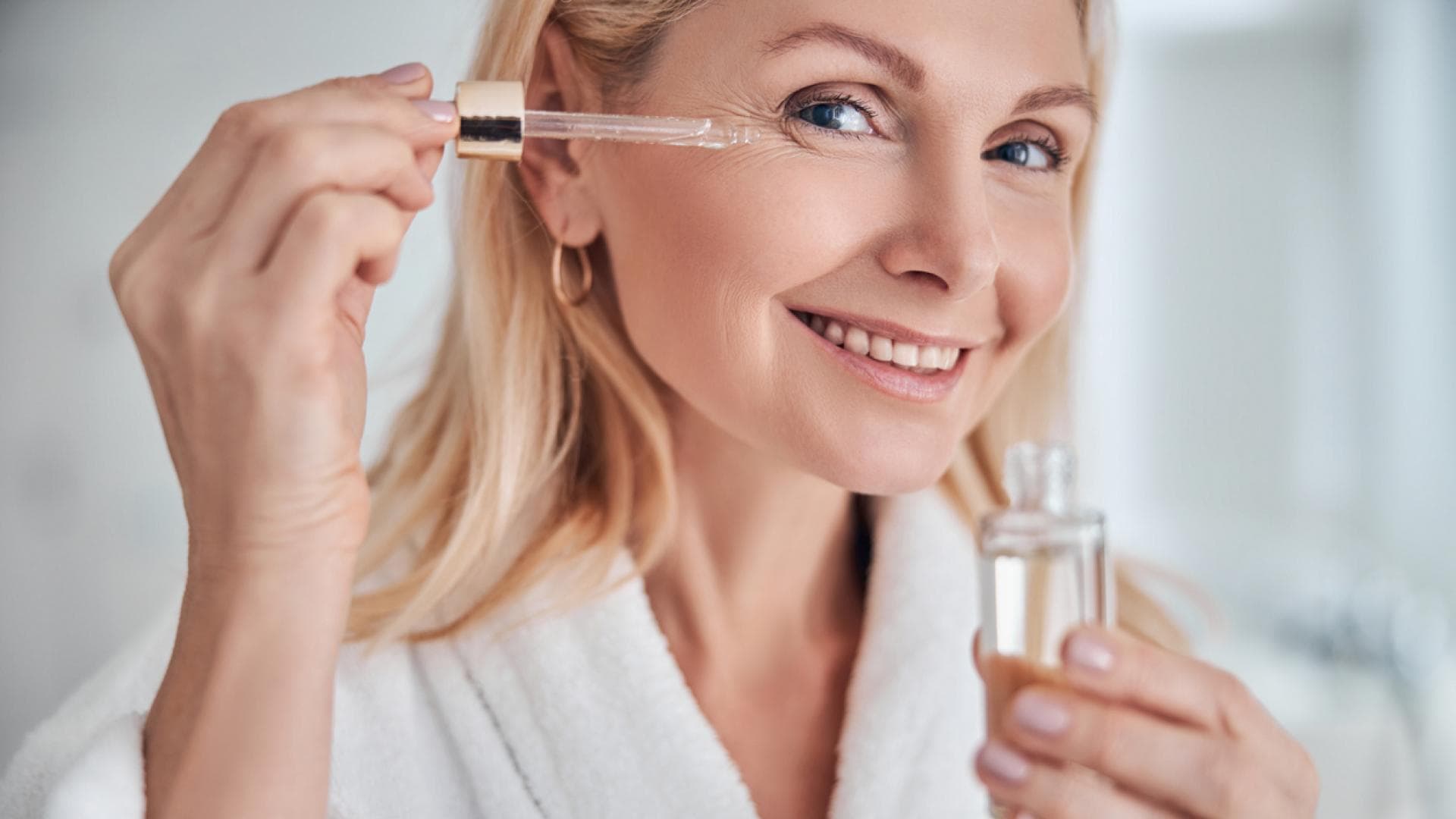 Frau trägt Gesichtsöl mit Pipette auf