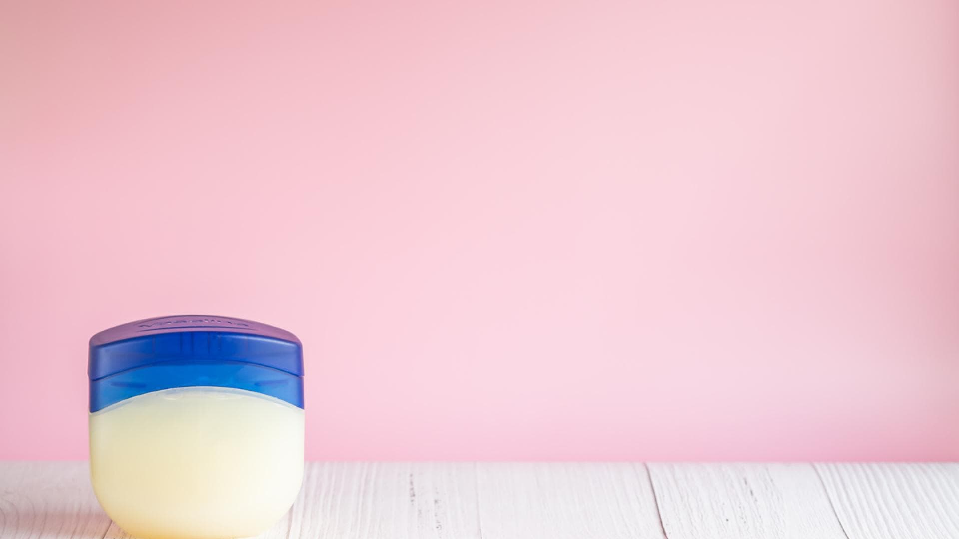 Tigel Vaseline auf Tisch vor pinker Wand