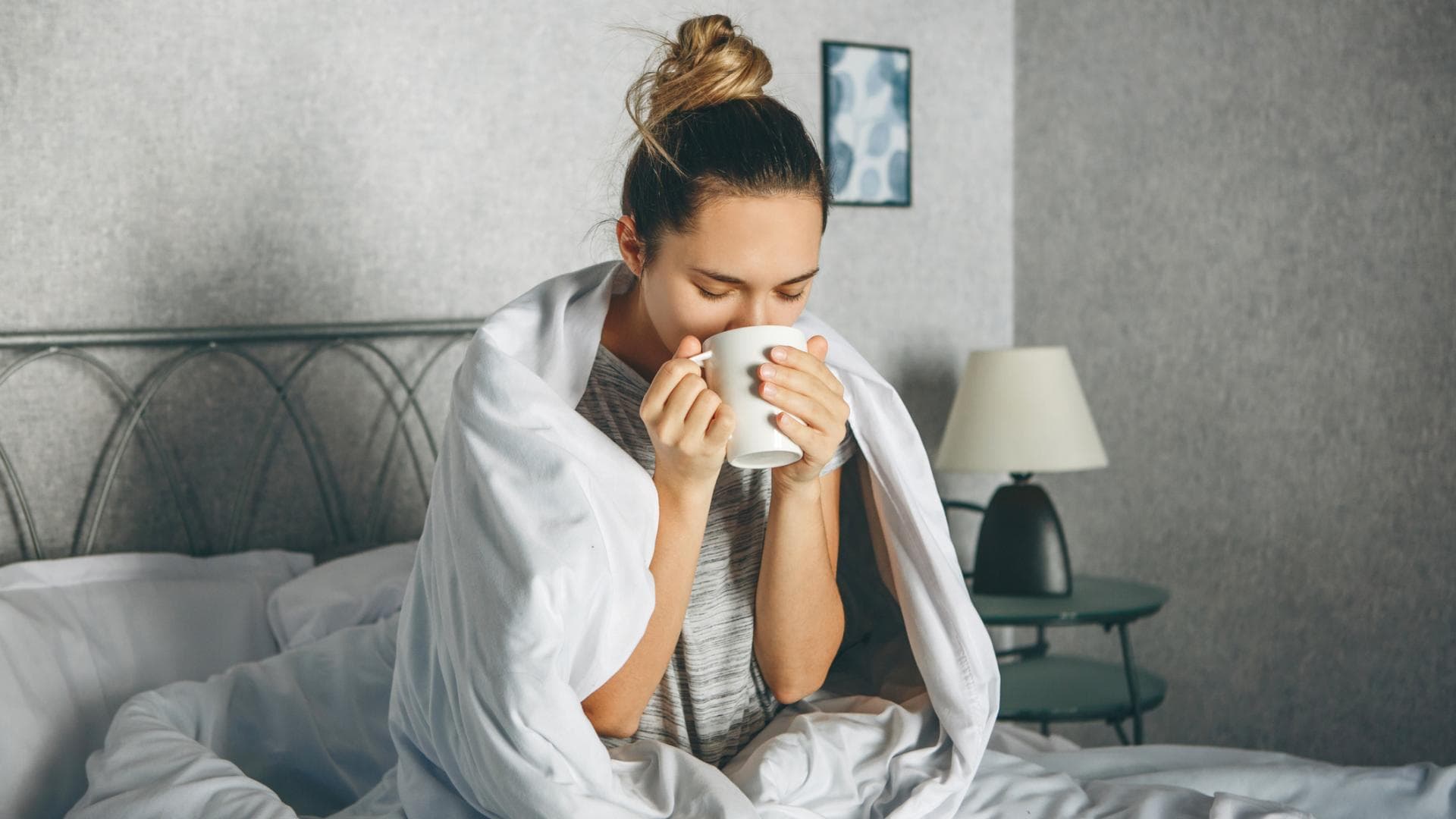 Kranke Frau trinkt Tee im Bett