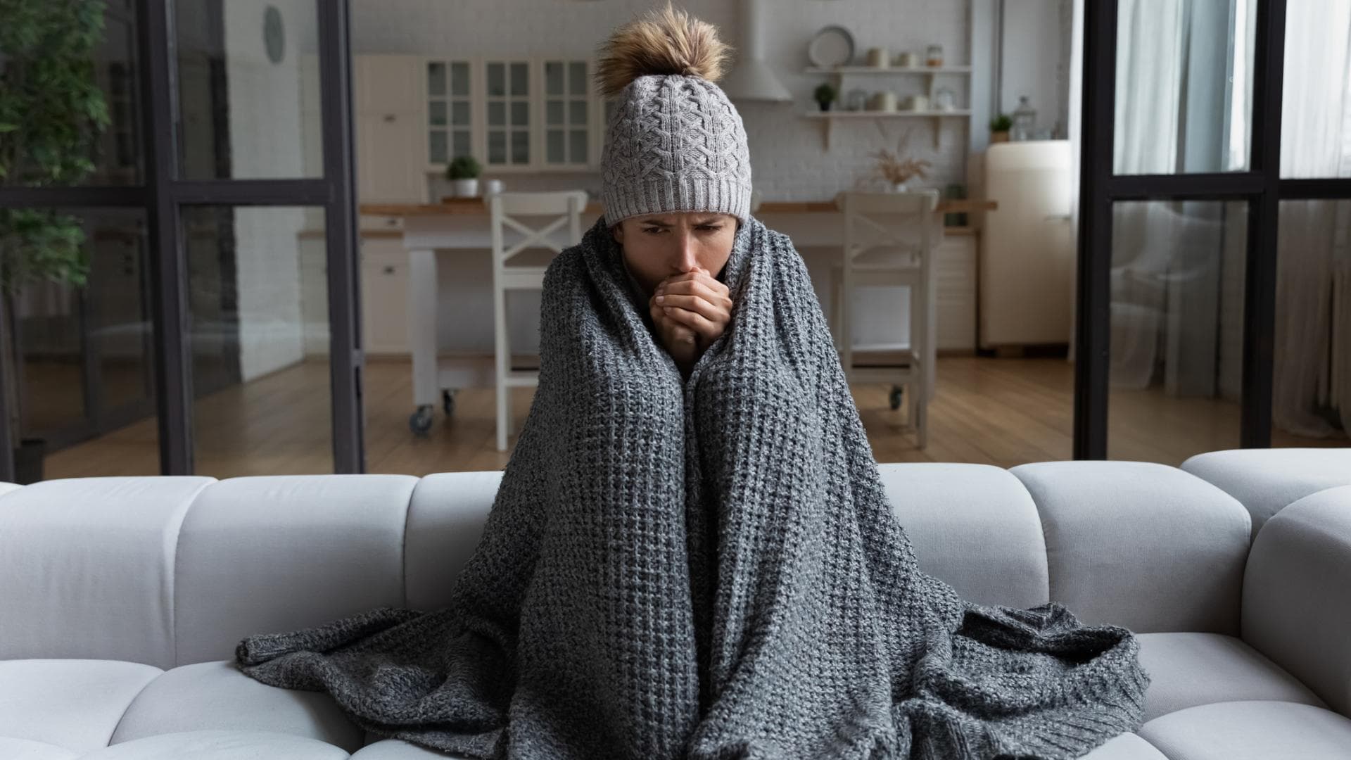 Frau mit Decke in kalter Wohnung. 