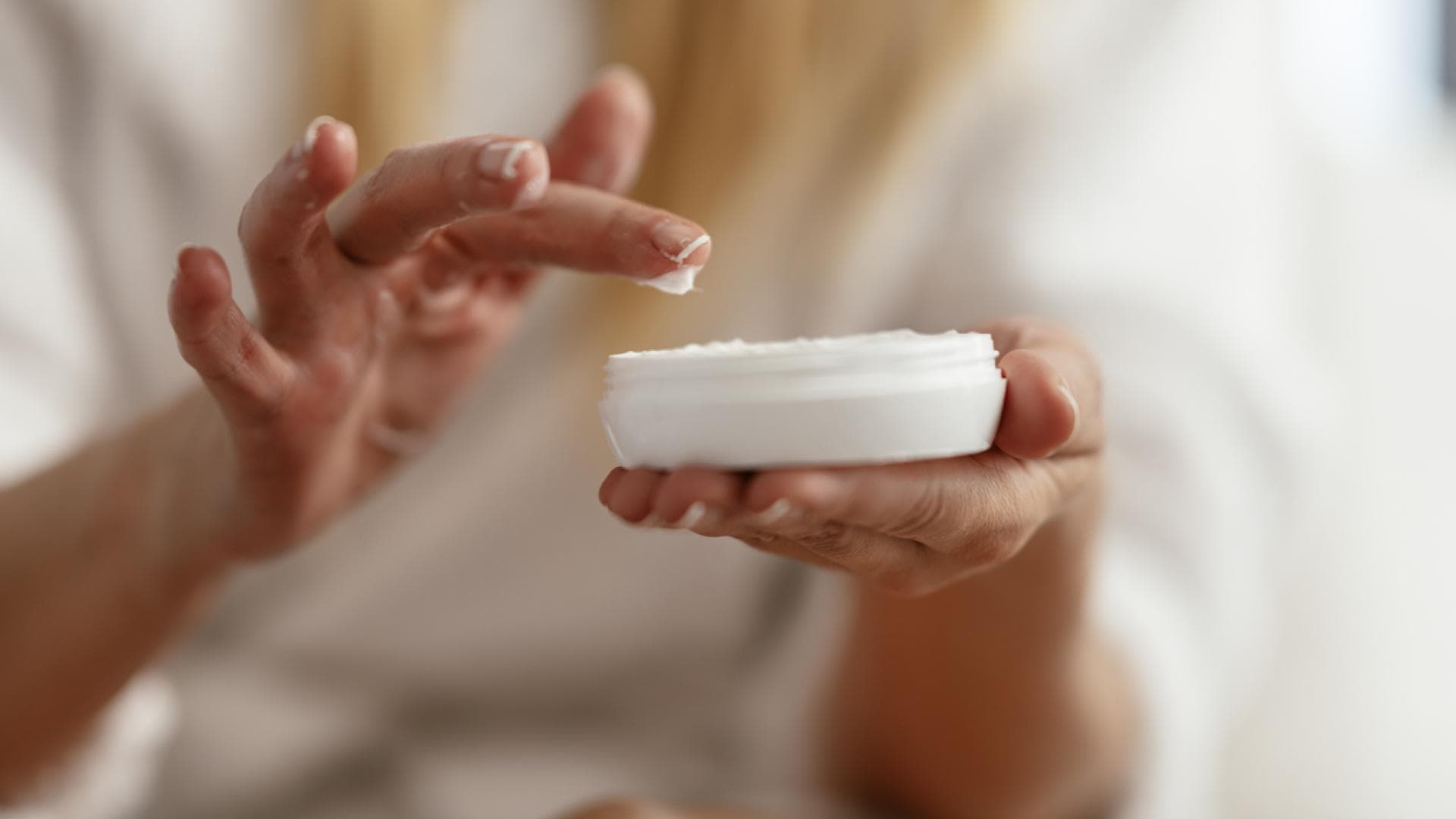 Frau nimmt Creme aus Tigel 