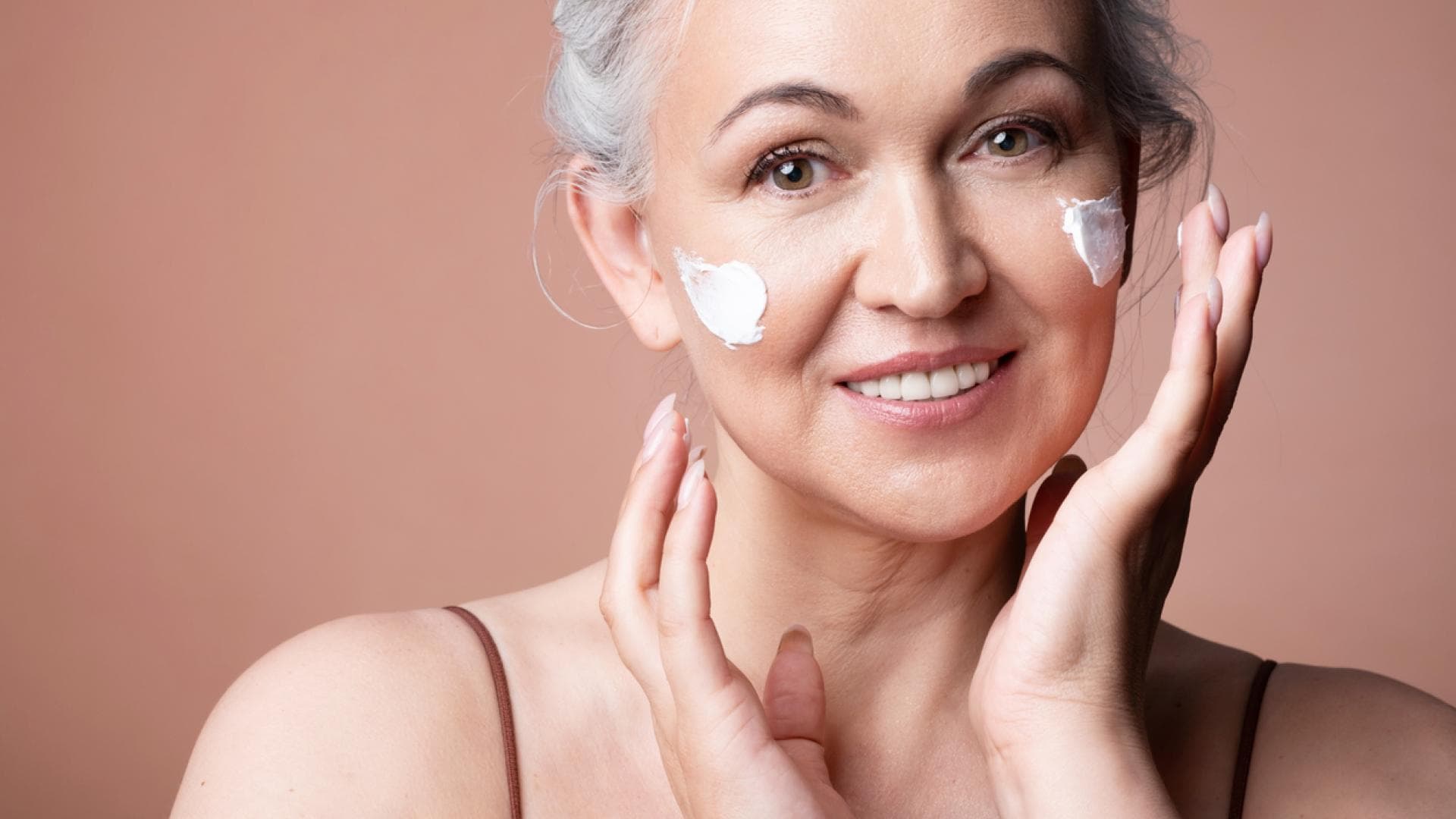 CC Cream für reife Haut Frau im mittleren Altern cremt Gesicht ein