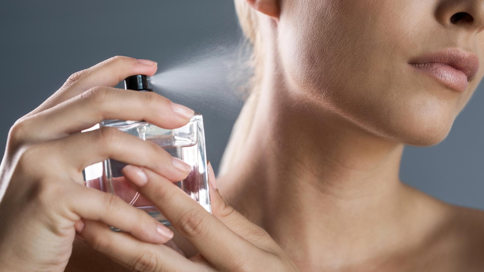 Frau sprüht Parfum auf ihren Hals