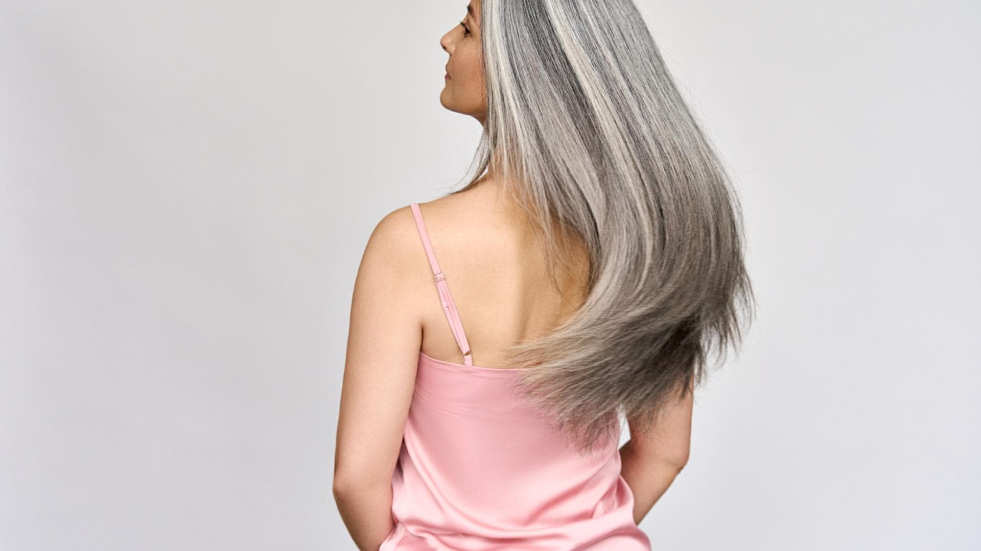 Gsunde Haare trotz hormoneller Umstellung im Alter Rüclansicht einer reifen Frau mit langen grauen Haaren