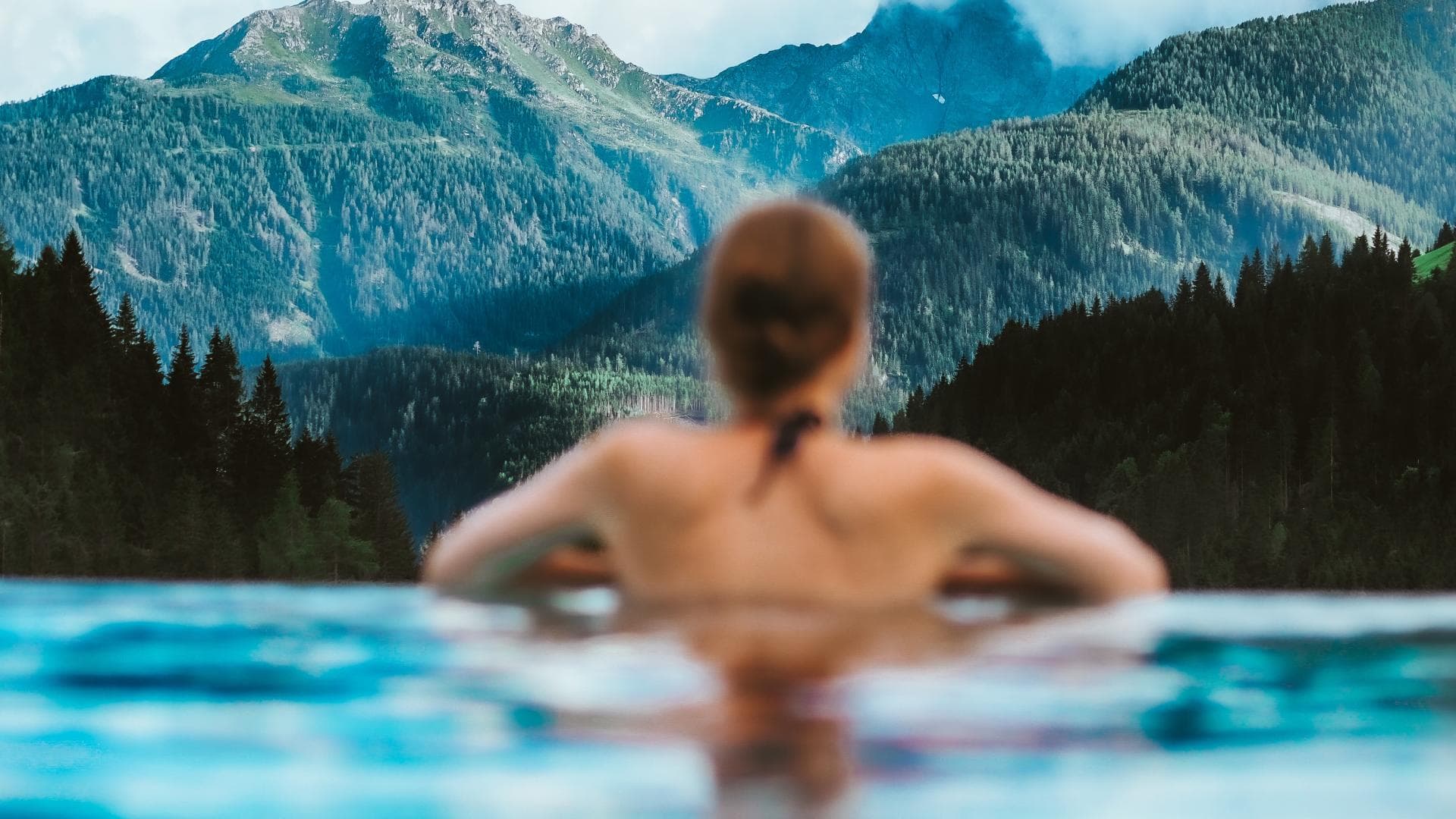 Frau im Pool mit Blick auf die Berge Frau im Pool mit Blick auf die Berge
