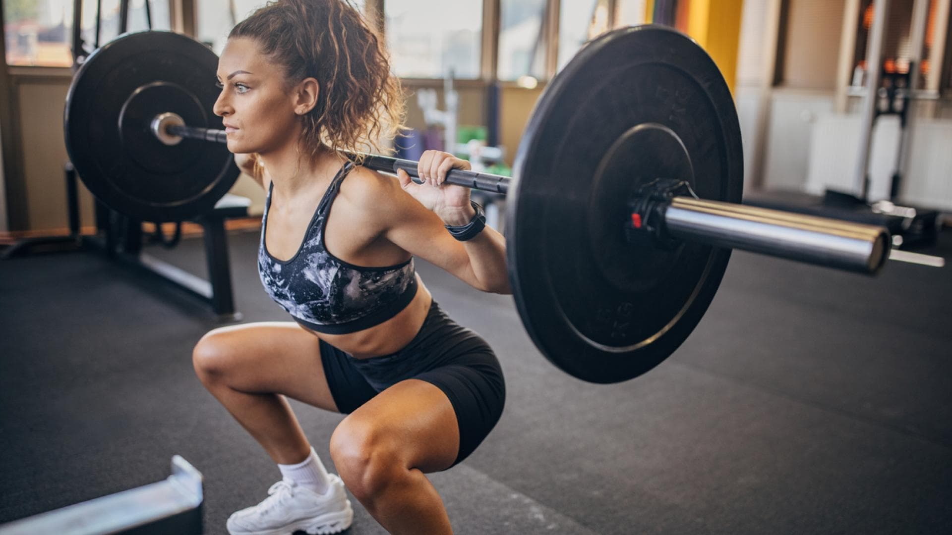 Frau mit Langhantel macht Squats