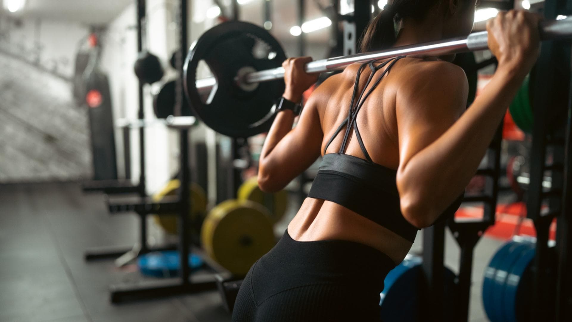 Rückenaufnahme einer Frau, die Squats mit Langhantel macht