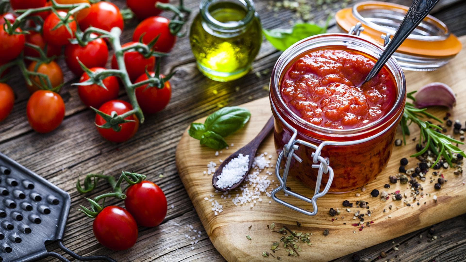 Hausgemachte Tomatensoße in Glas mit frischen Zutaten auf Brett