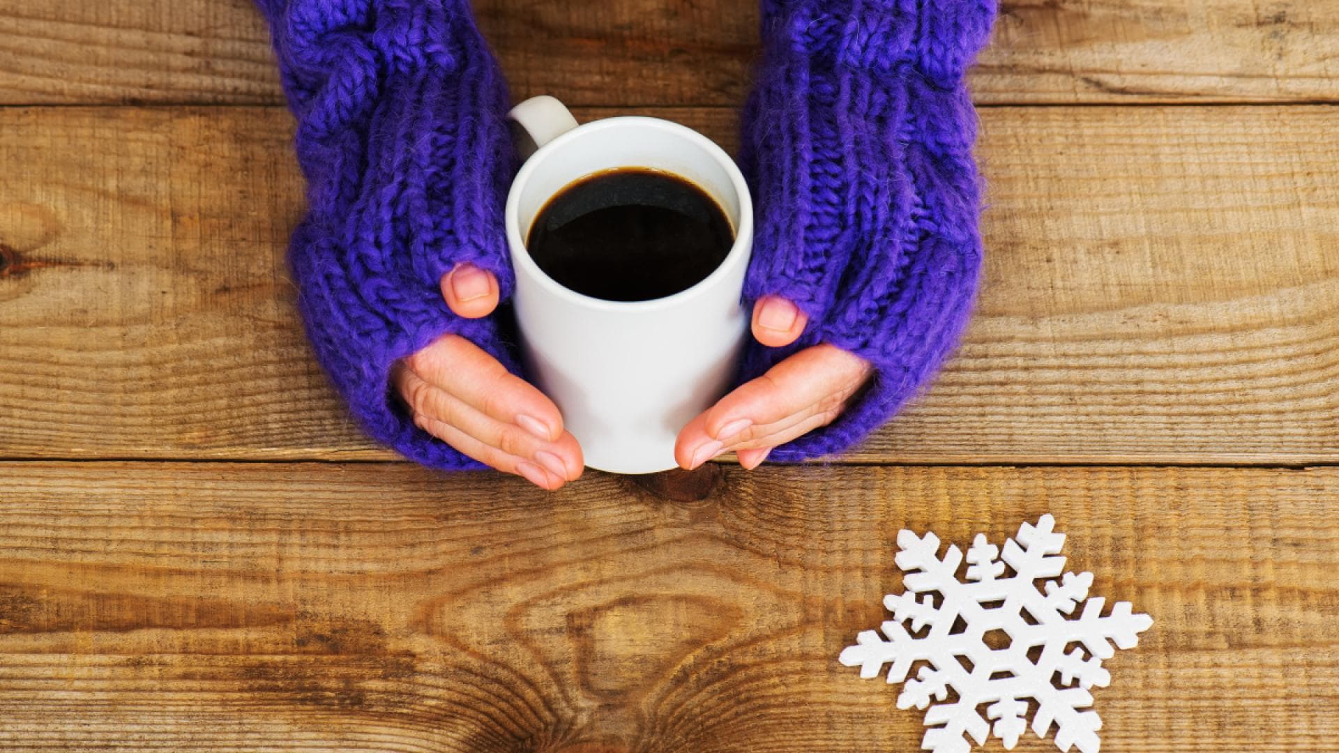 Frau wärmt Hände an einer Tasse Kaffee