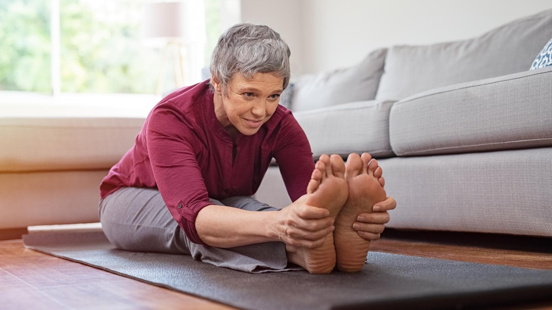 Ältere Frau dehnt sich auf Yogamatte