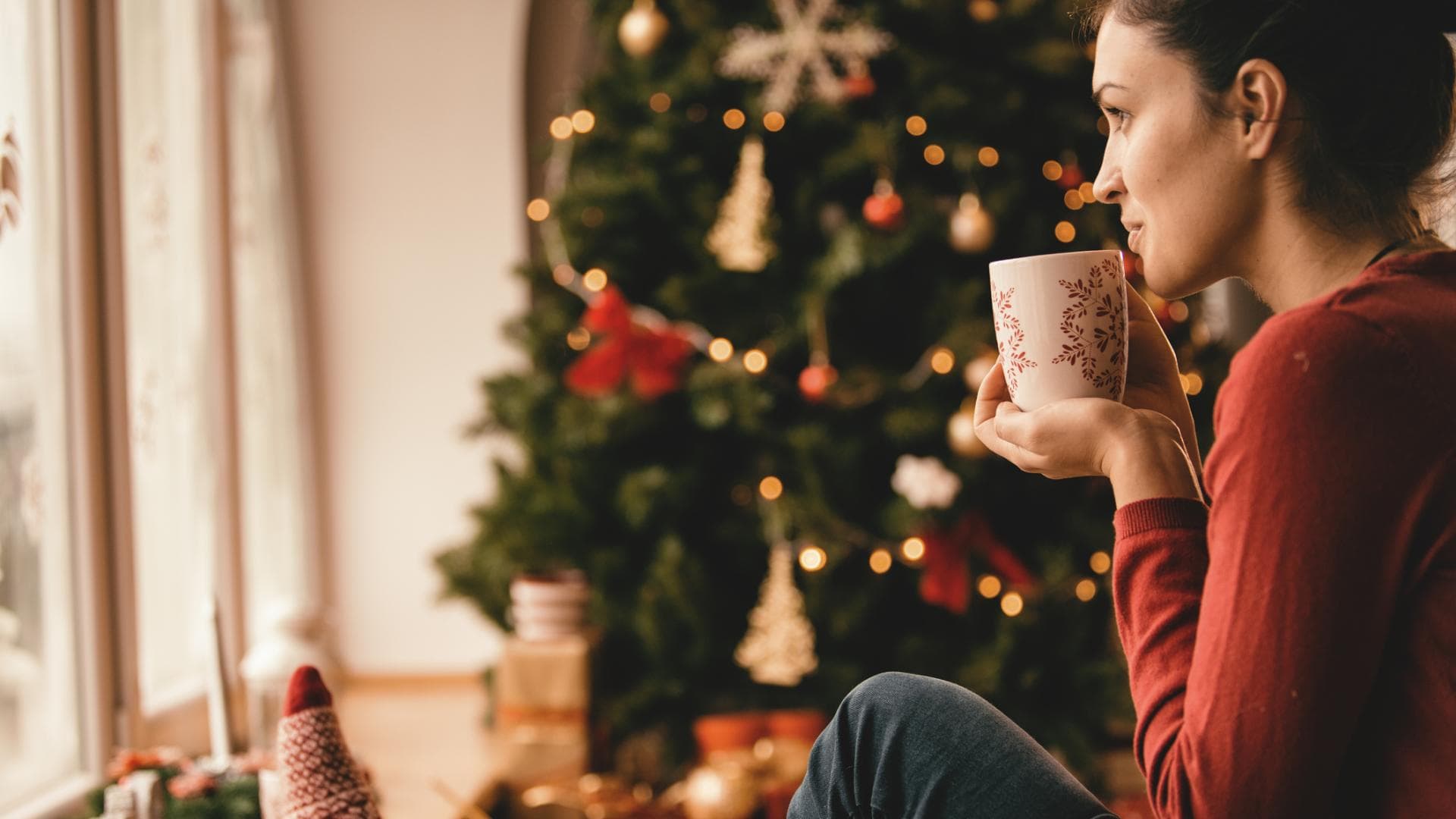 Frau mit Tee unter Weihnachtsbaum
