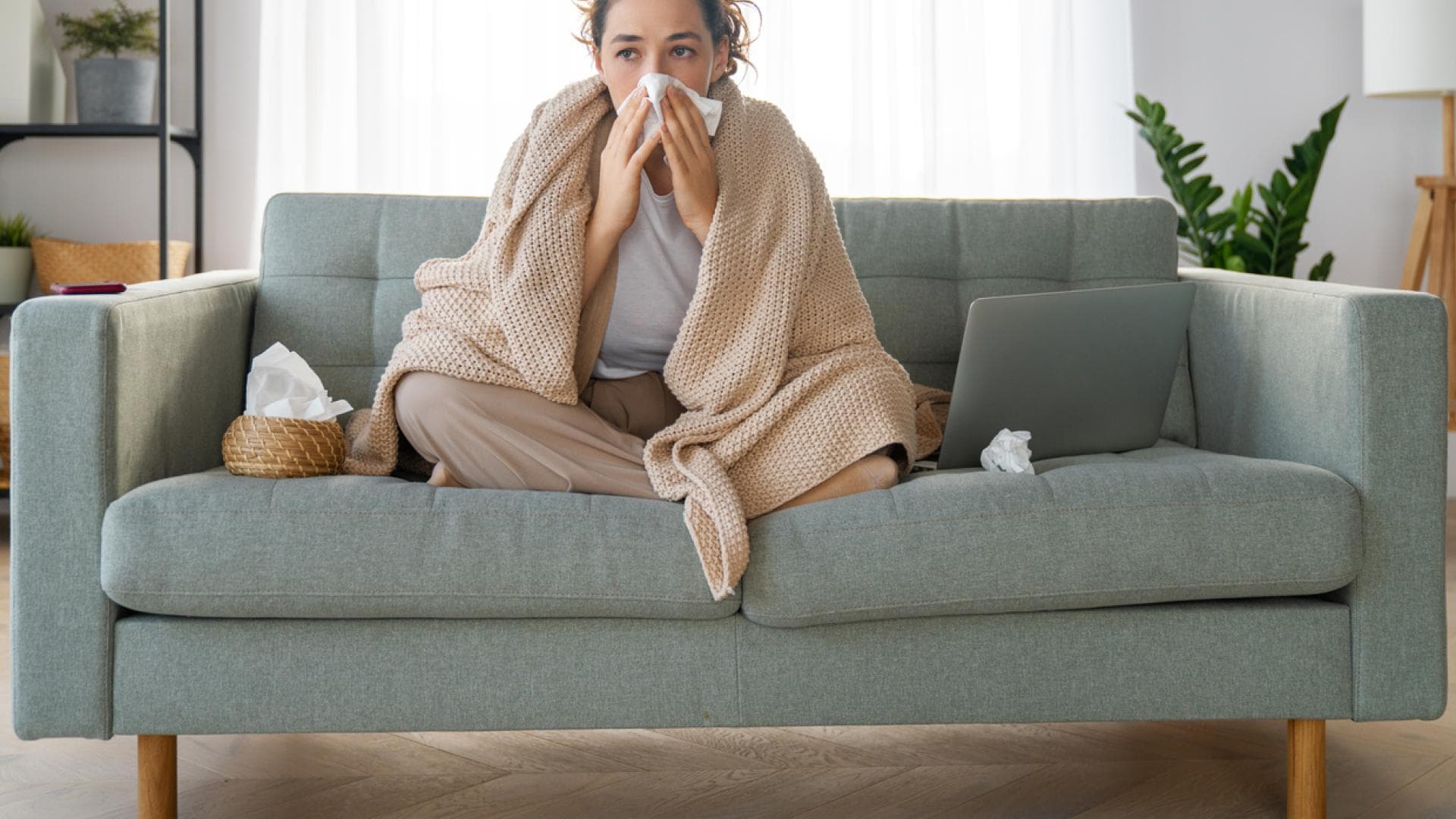 Frau mit Erkältung sitzt auf Couch