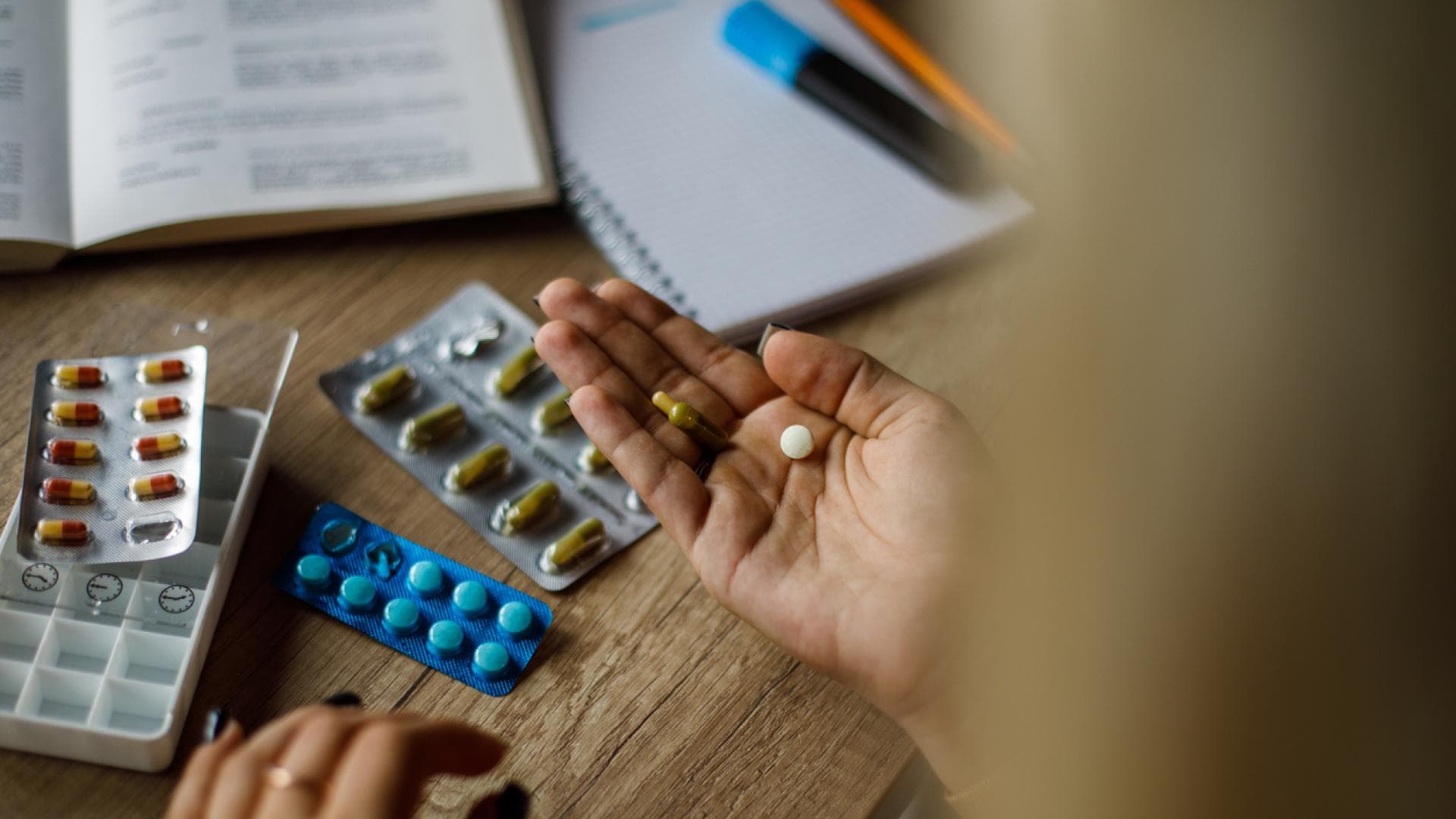 Frau hat verschiedene Filmtabletten vor sich liegen