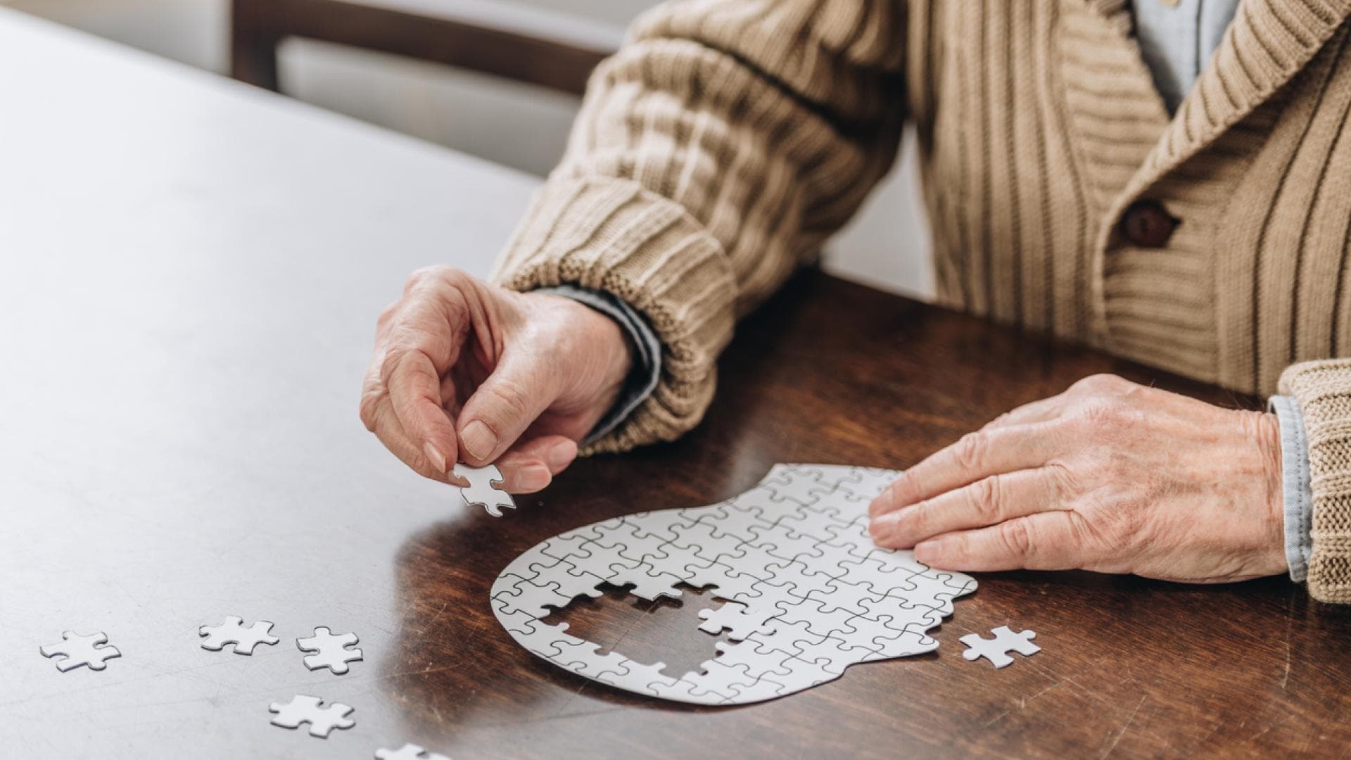 Alter Mann puzzelt auf Tisch