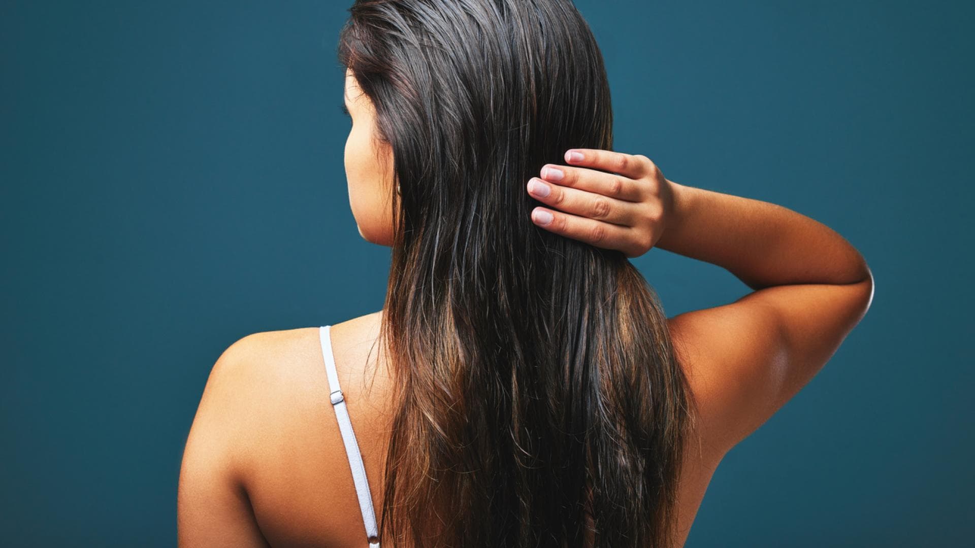 Rückenansicht einer Frau, die ihre Haare mit den Fingern durchkämmt