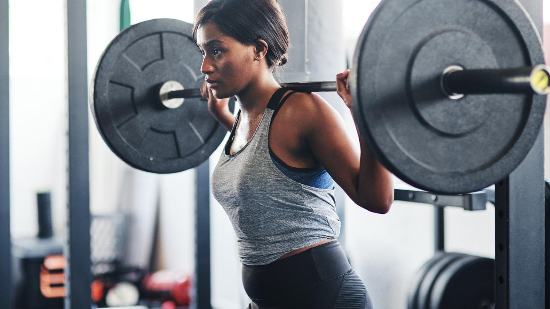 Frau macht Back-Squats im Squat-Rack
