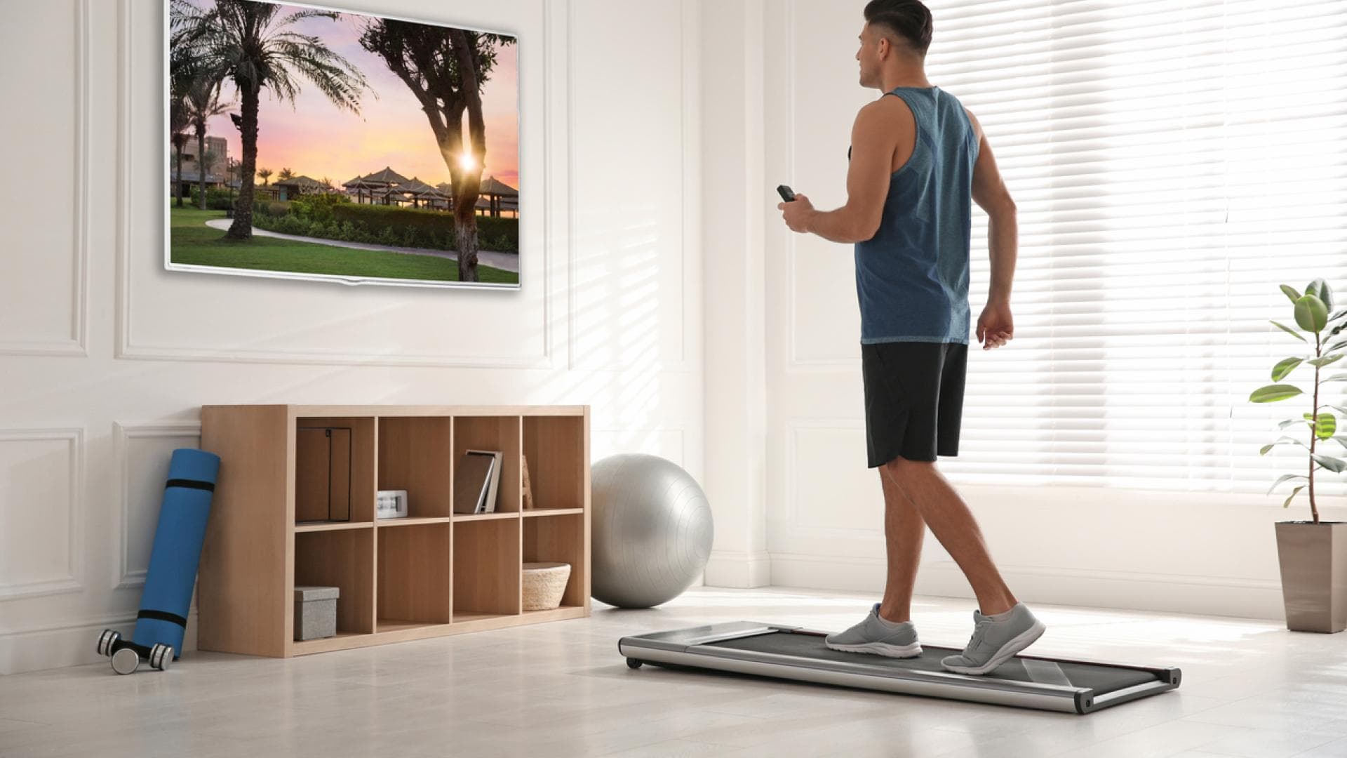 Mann geht auf kleinem Laufband im Wohnzimmer spazieren
