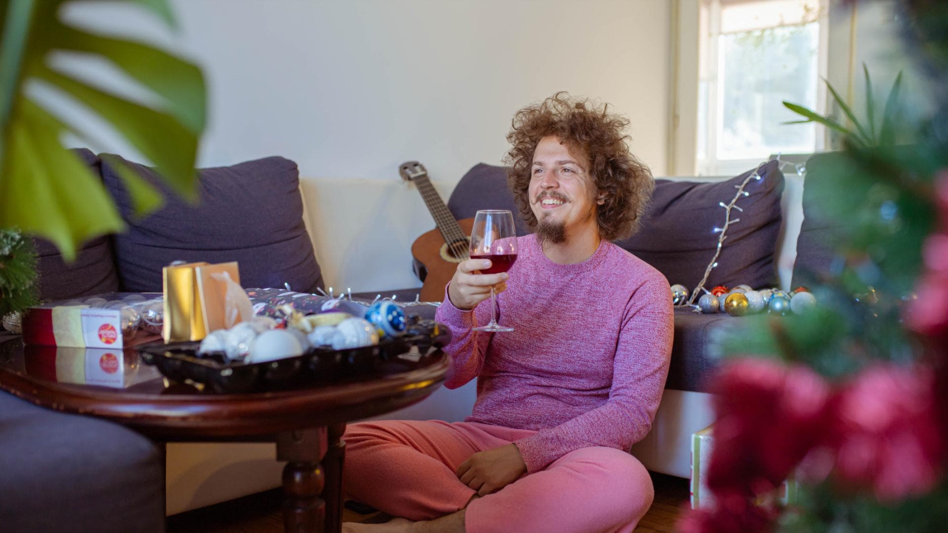 Mann sitzt mit Weinglas alleine vor dem Fernseher