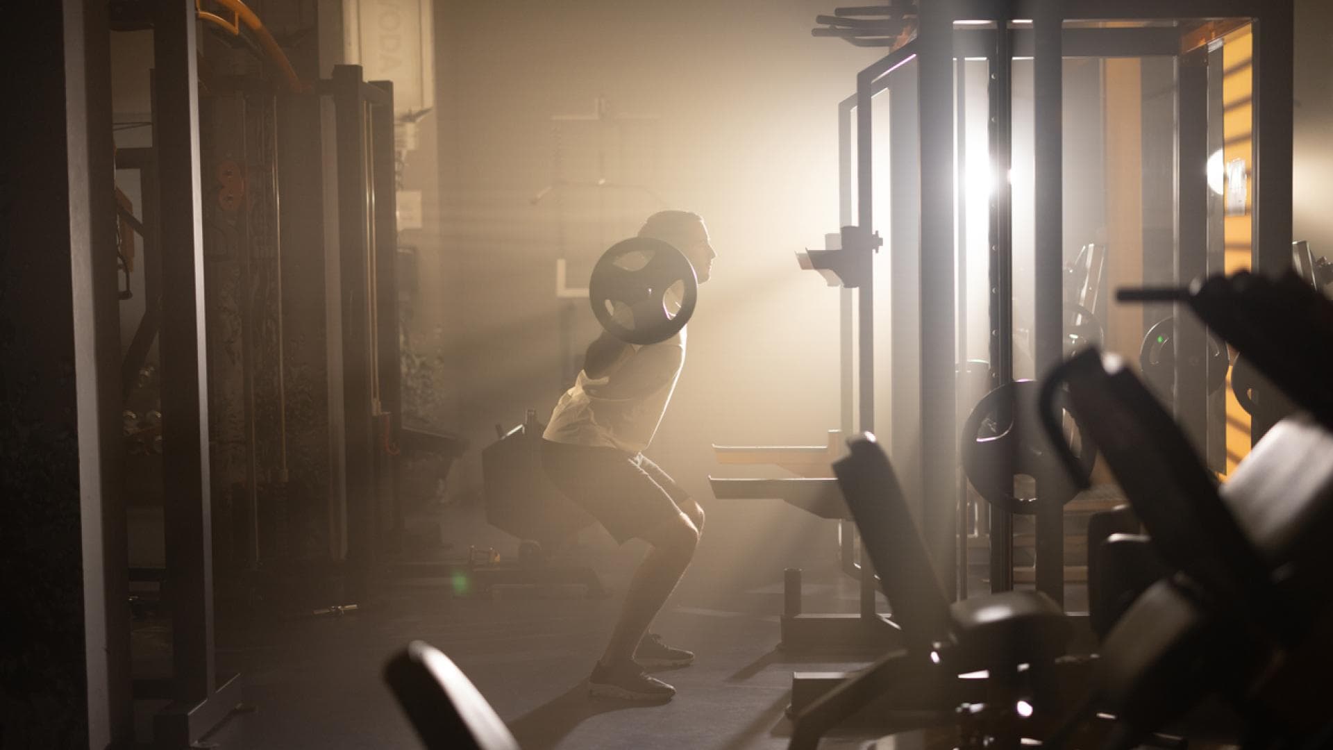 Mann macht Squats im Gym bei Sonnenaufgang