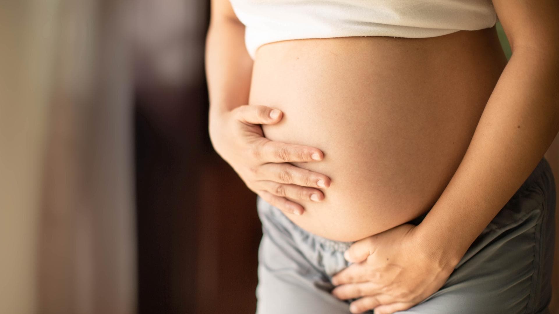 Schwangere Frau hält sich den Bauch