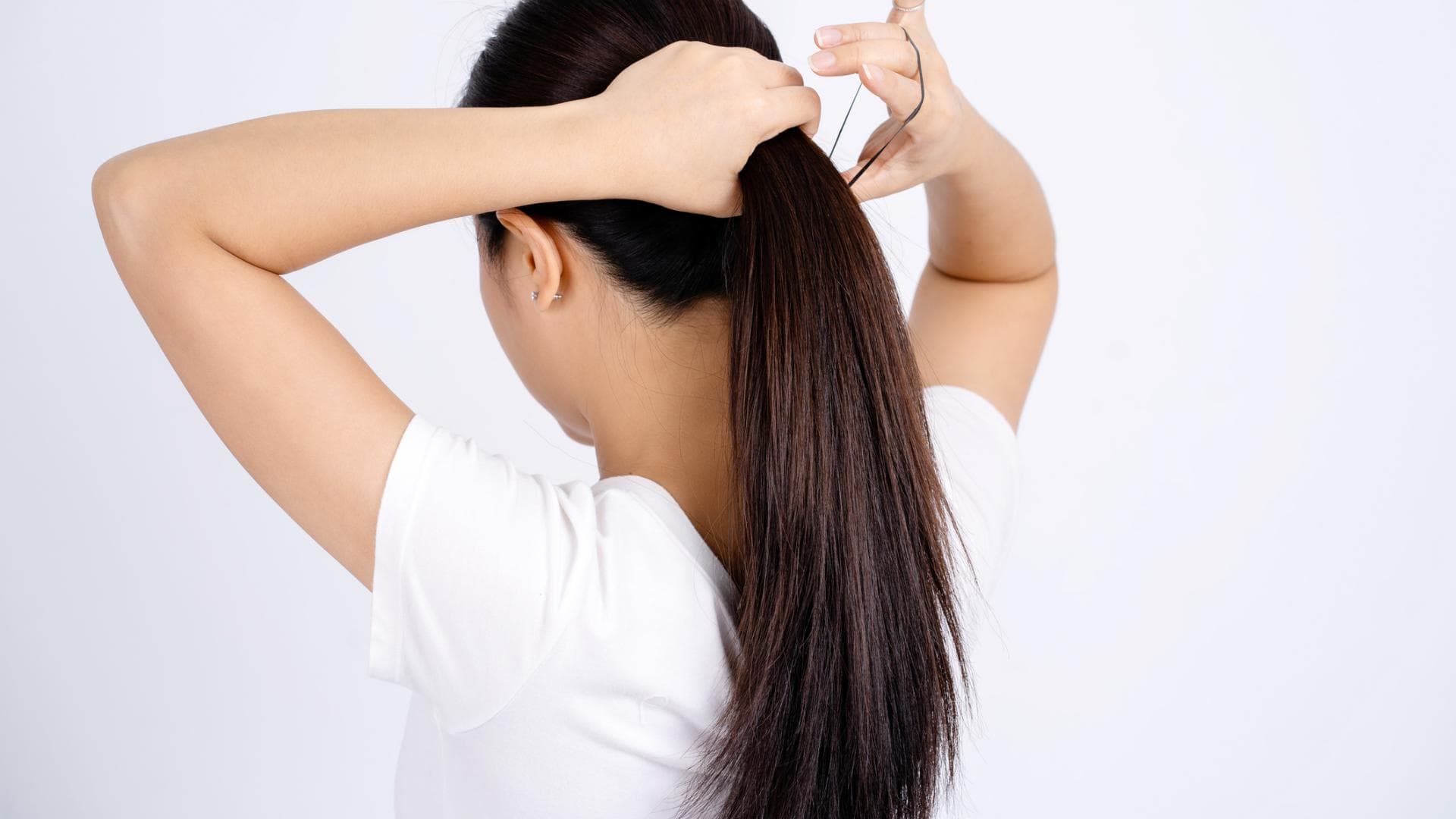 Frau bindet Haare zusammen