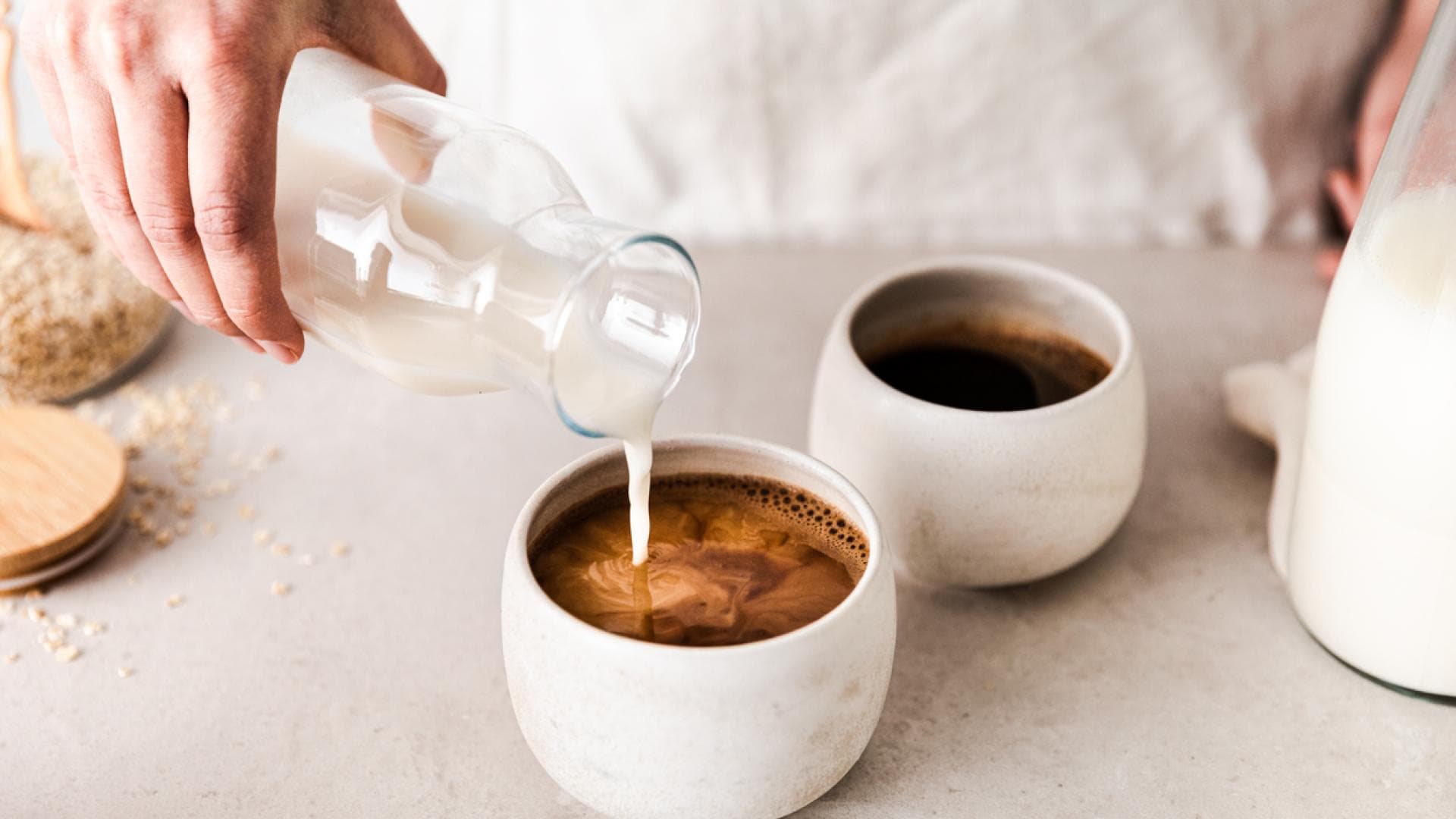 Hafermilch wird in den Kaffee gegossen