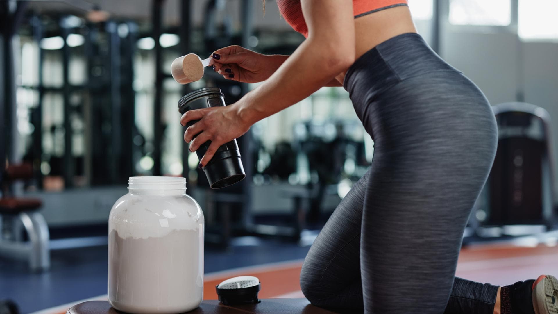 Frau im Fitnessstudio mischt sich Proteindrink