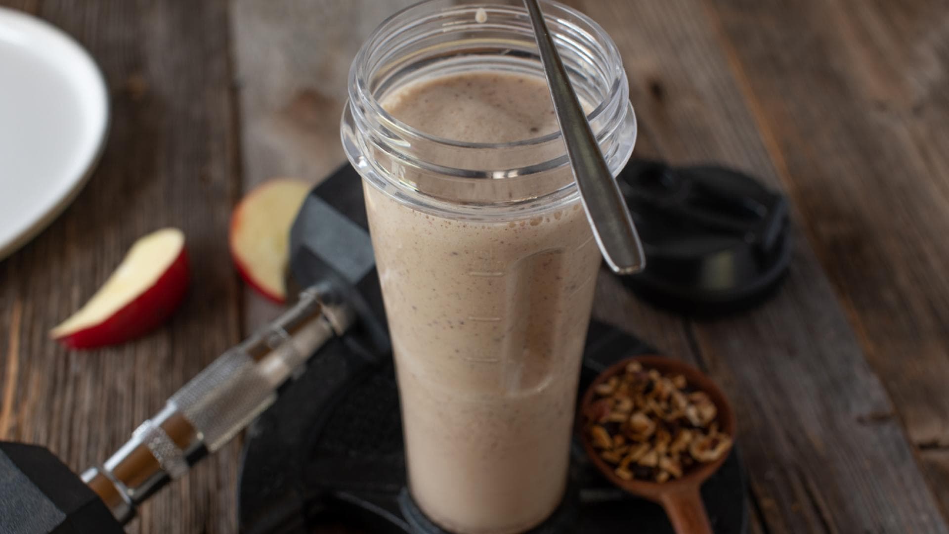 Proteinshae und Hantel auf Holztisch