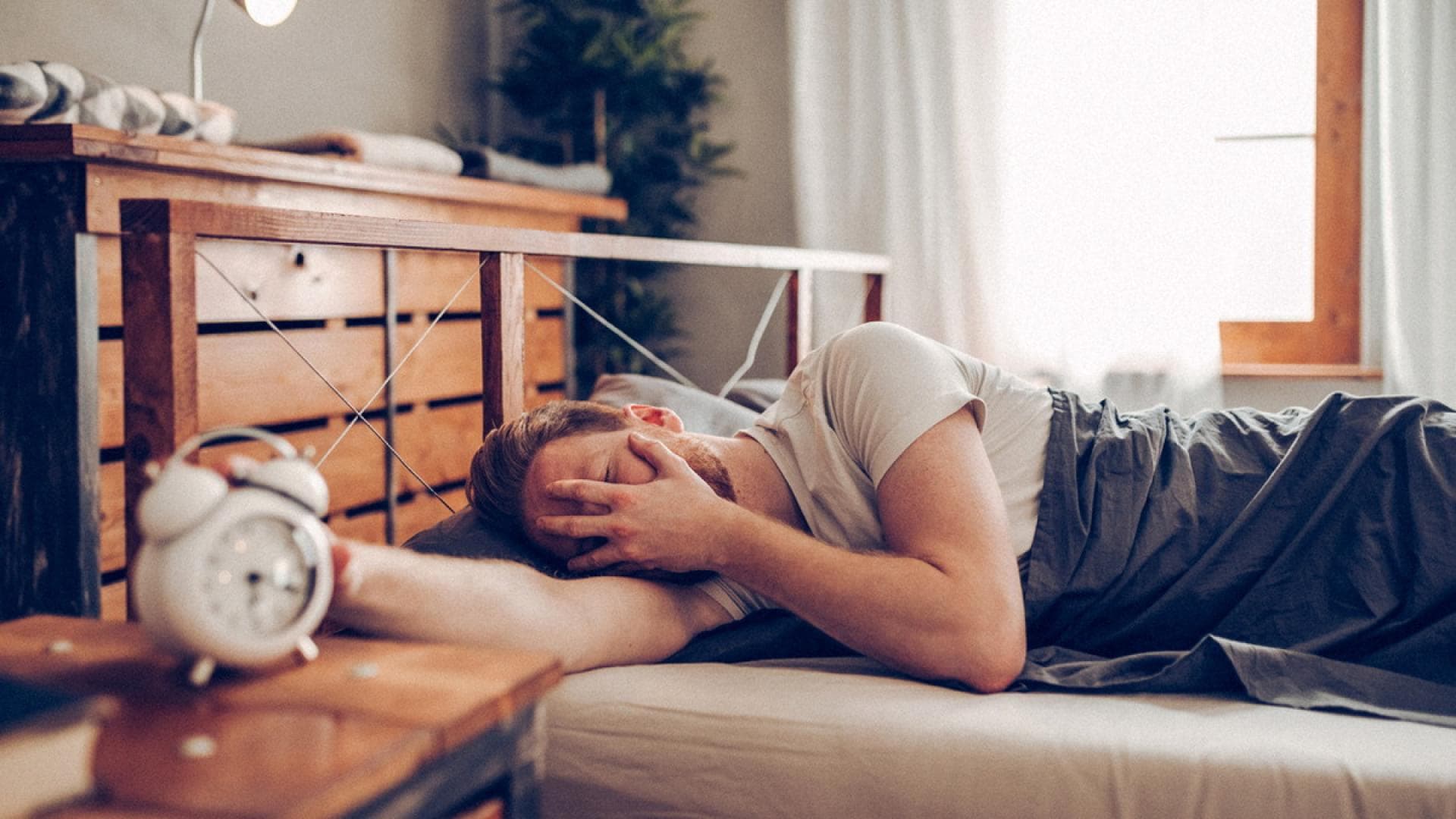 Müder Mann hat Schwierigkeiten morgens aus dem Bett zu kommen